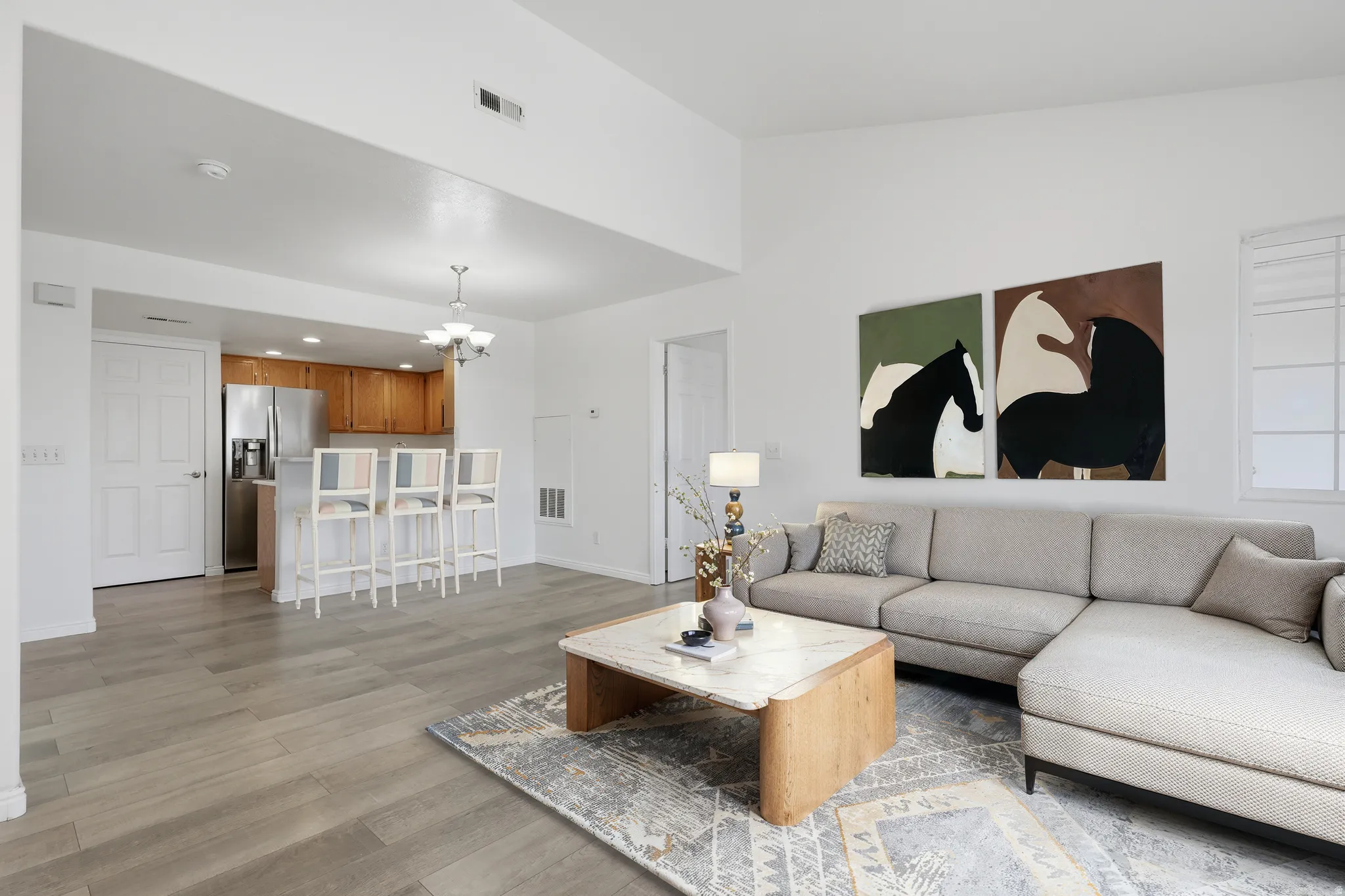 Living room with light wood-style floors and suspended lighting