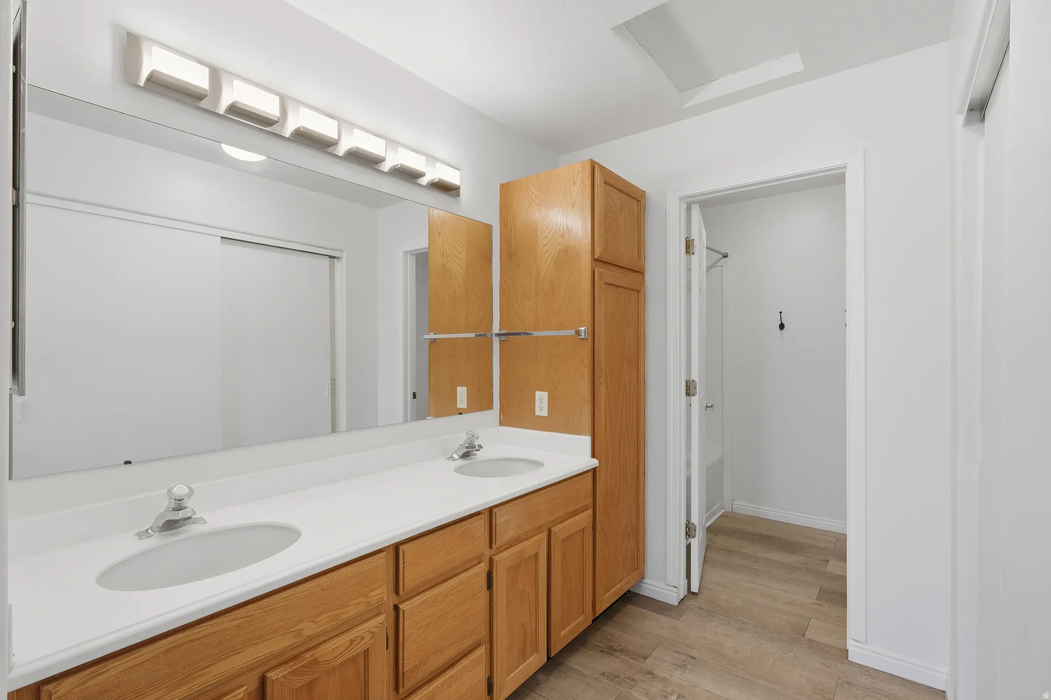 Bathroom featuring double vanity and light wood-style flooring