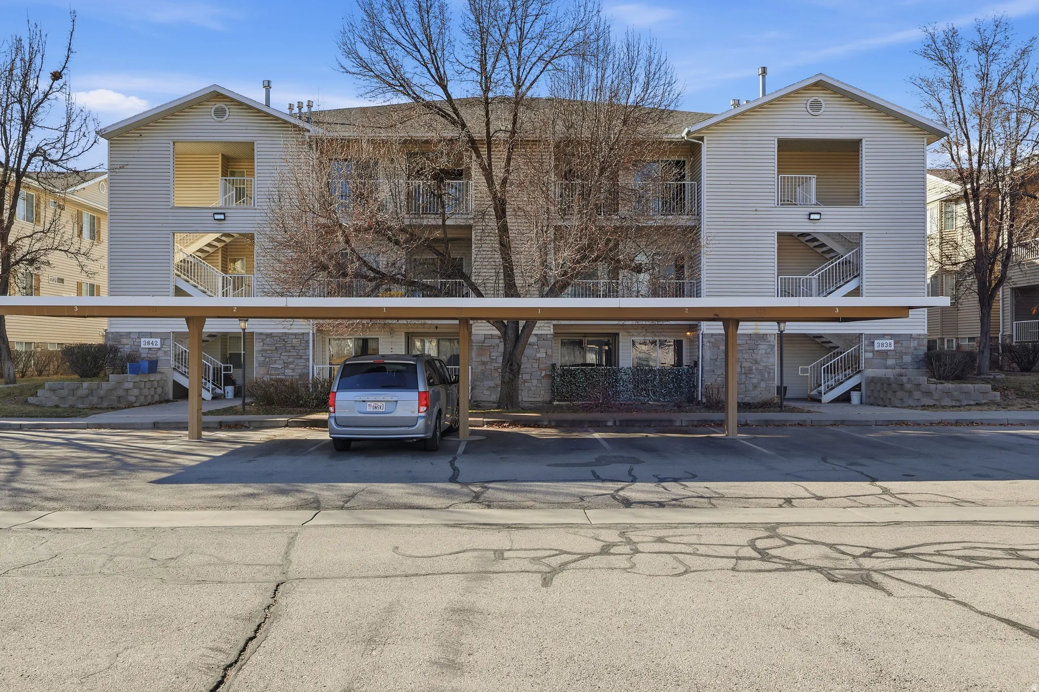 View of apartment building / complex featuring stairs and covered parking