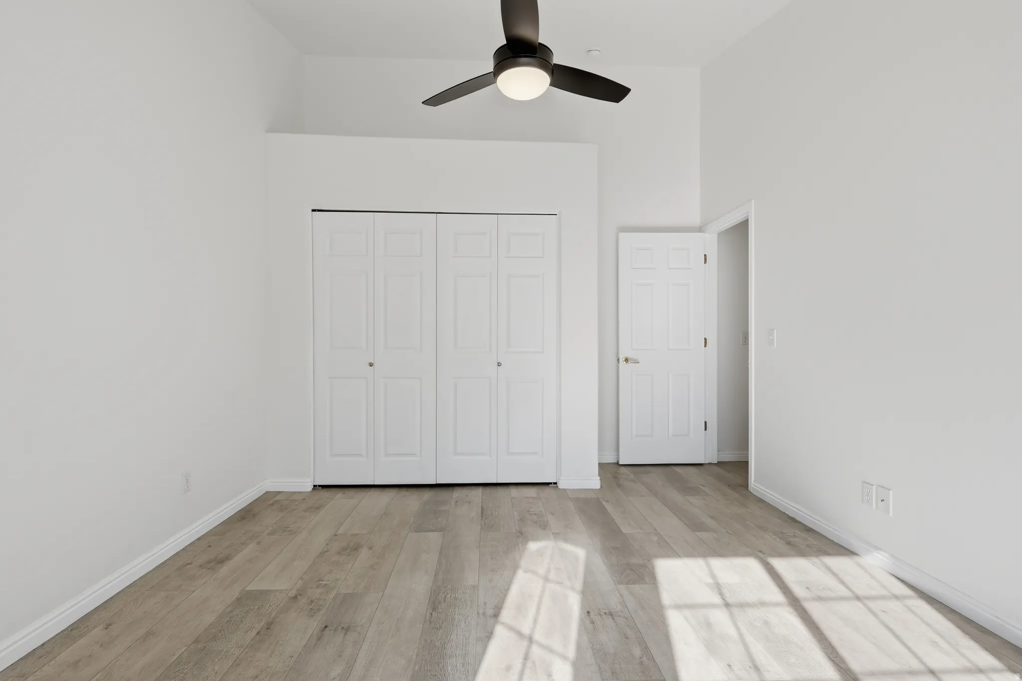 Unfurnished bedroom with a high ceiling, light wood-style flooring, ceiling fan, and a closet