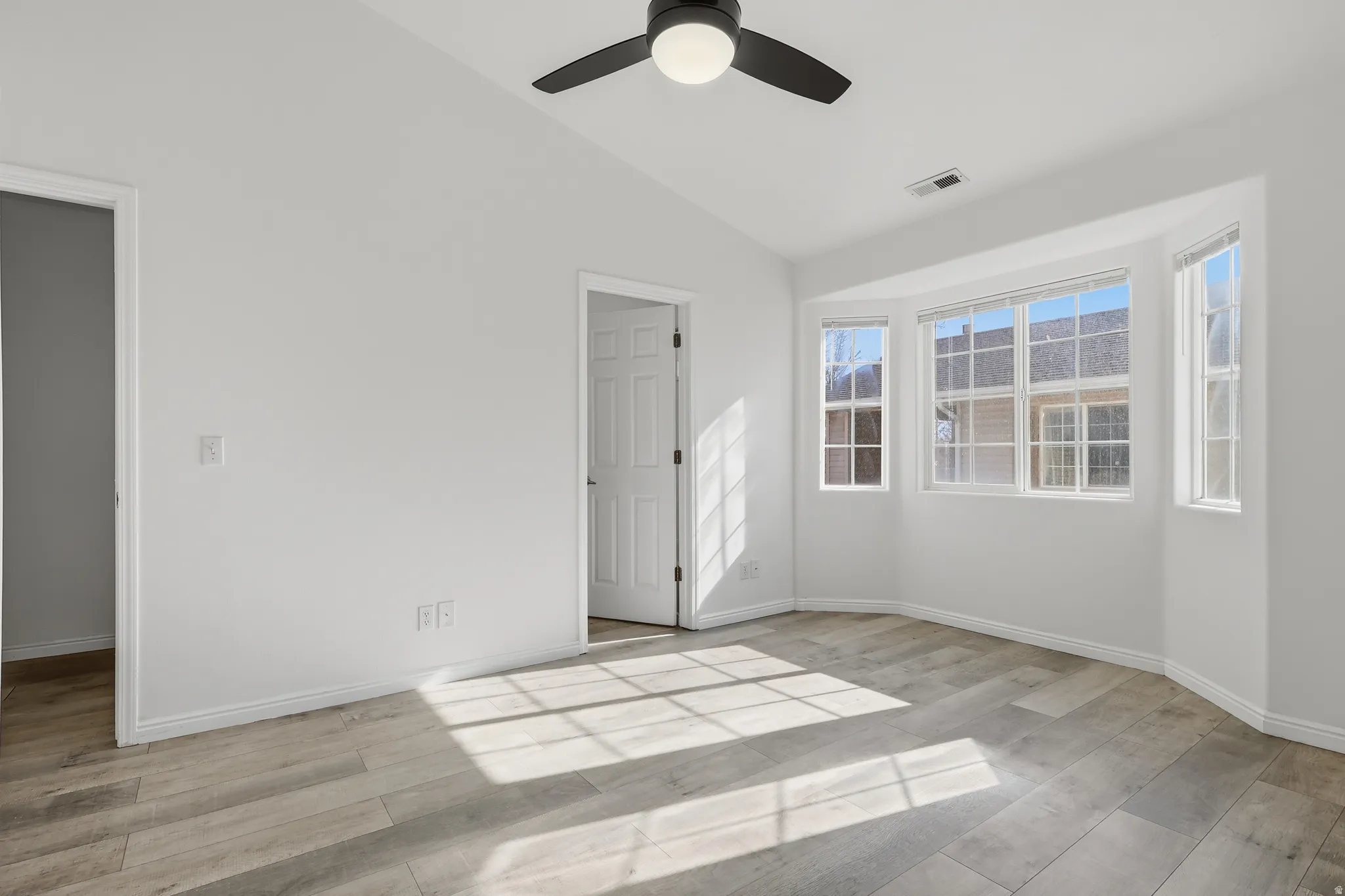 Unfurnished bedroom with lofted ceiling, light wood-style floors, and a ceiling fan