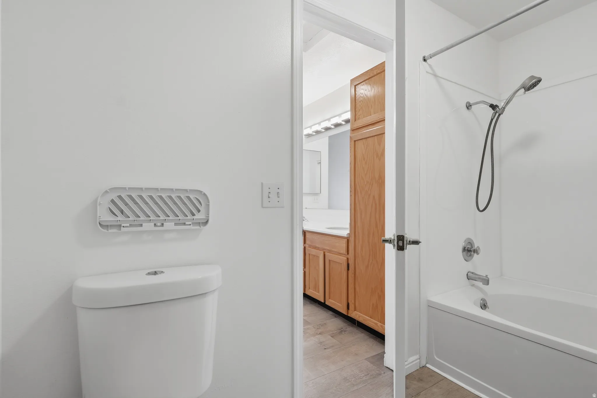 Full bath featuring bathing tub / shower combination, vanity, and light wood-style flooring