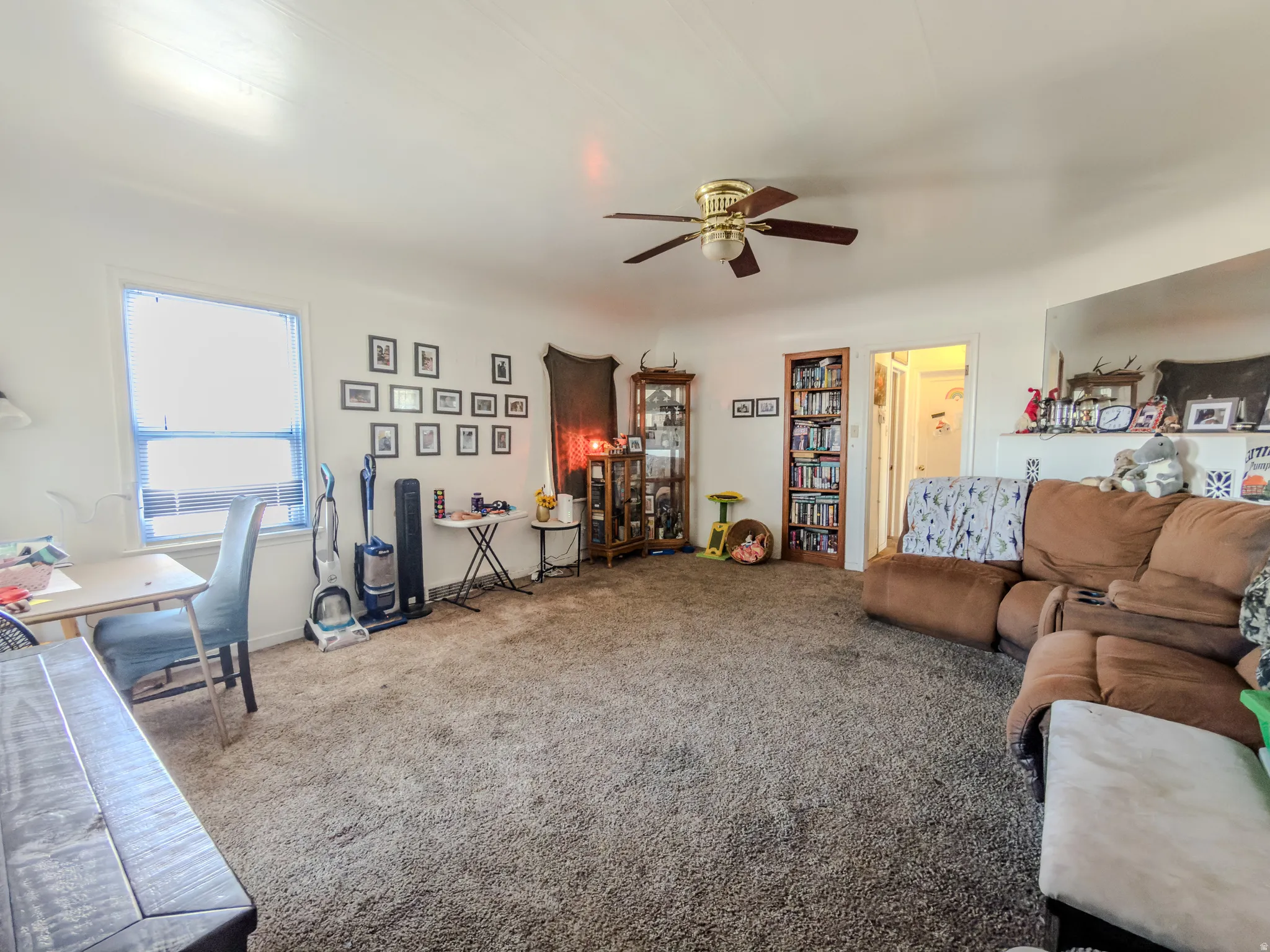 Carpeted living area with ceiling fan