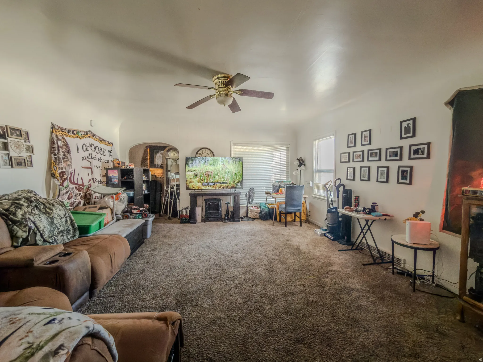 Carpeted living area with a ceiling fan and arched walkways