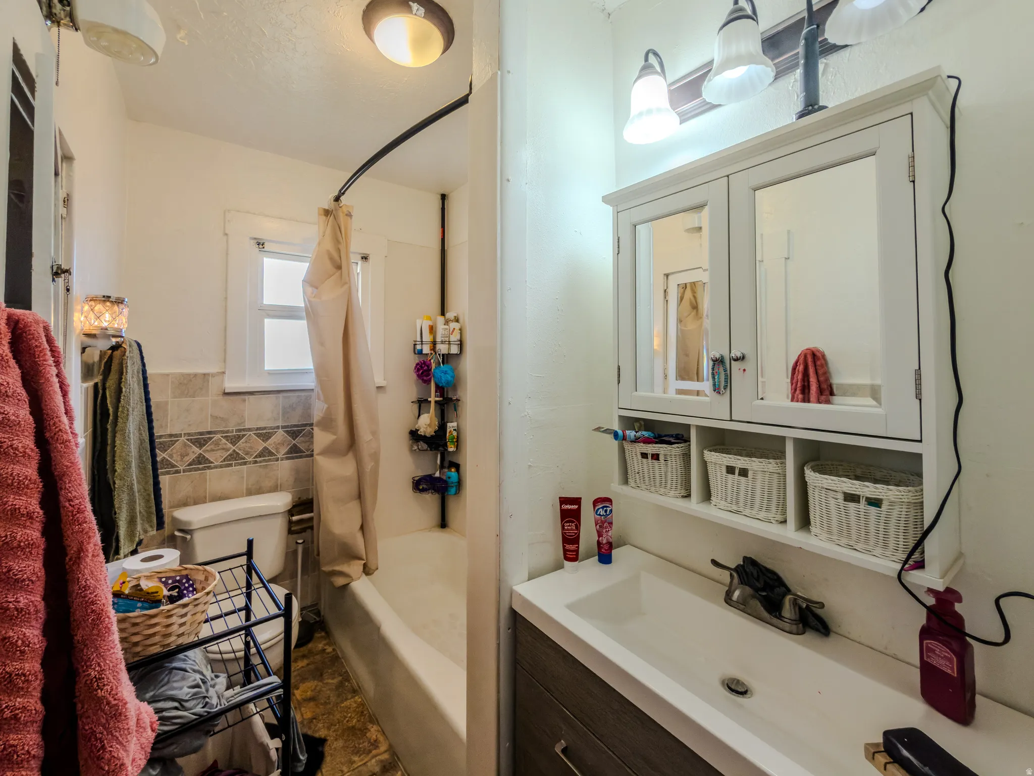 Full bathroom featuring vanity, shower / tub combo, tile walls, and wainscoting