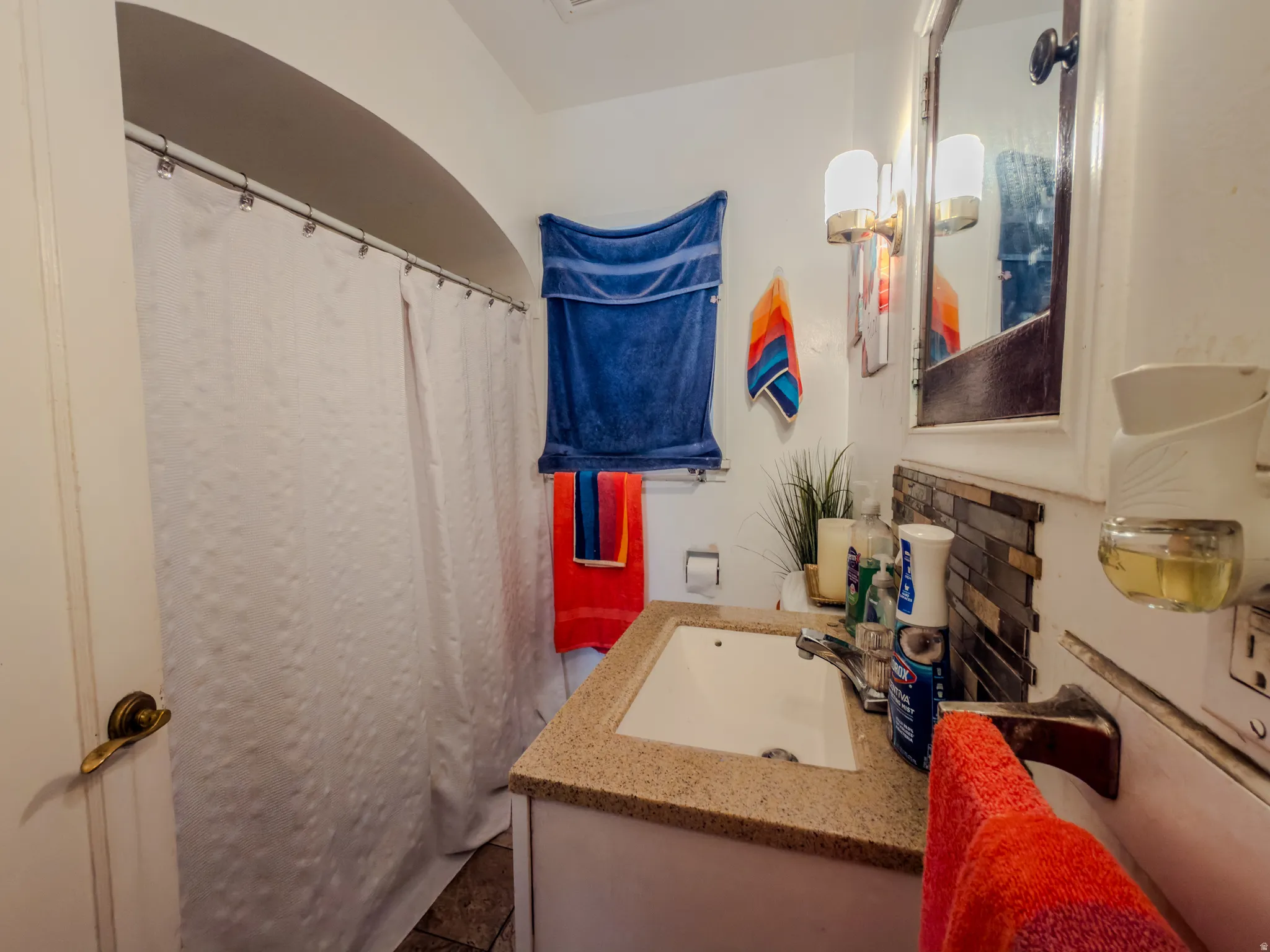 Full bath featuring a shower with shower curtain, vanity, and tasteful backsplash