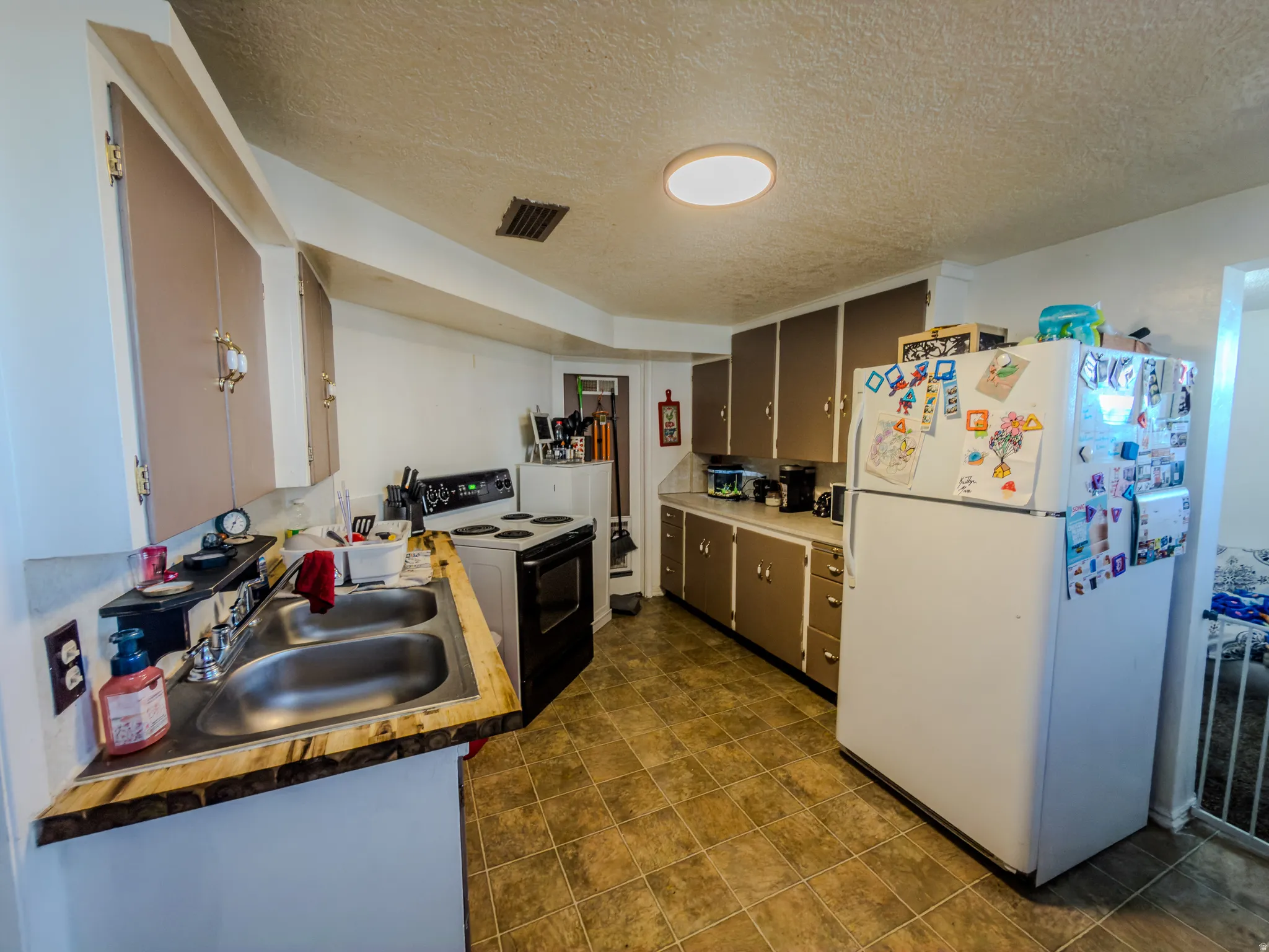 Kitchen featuring freestanding refrigerator, electric stove, a textured ceiling, and light countertops