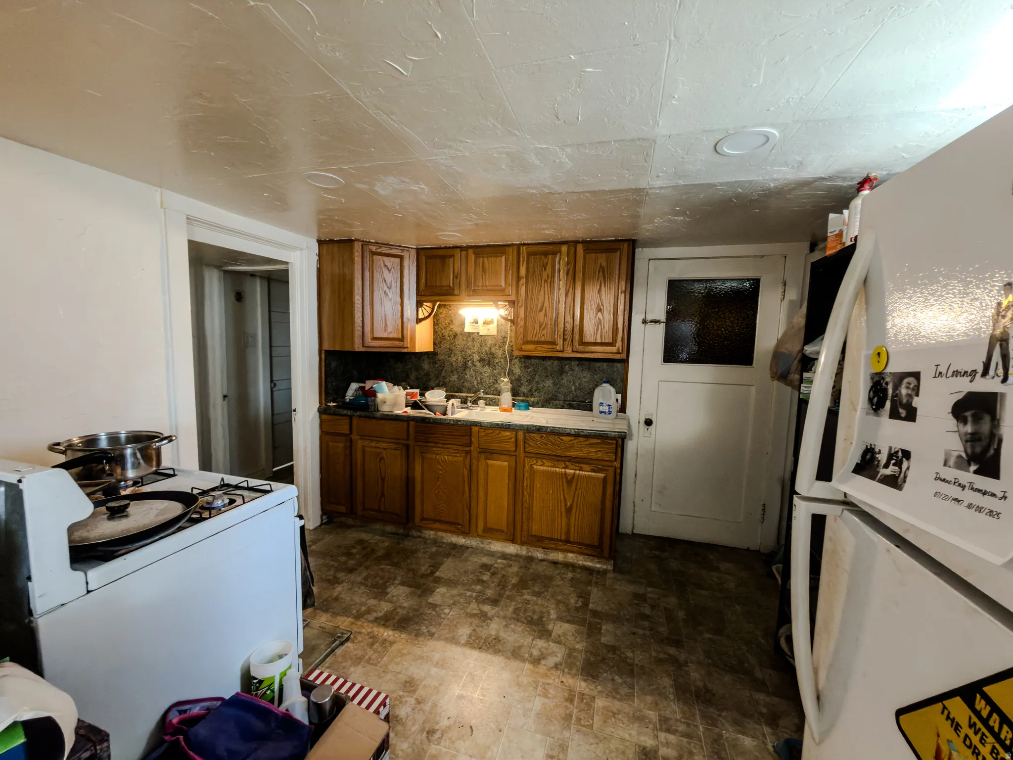 Kitchen with wood finish cabinets, white appliances, and light countertops