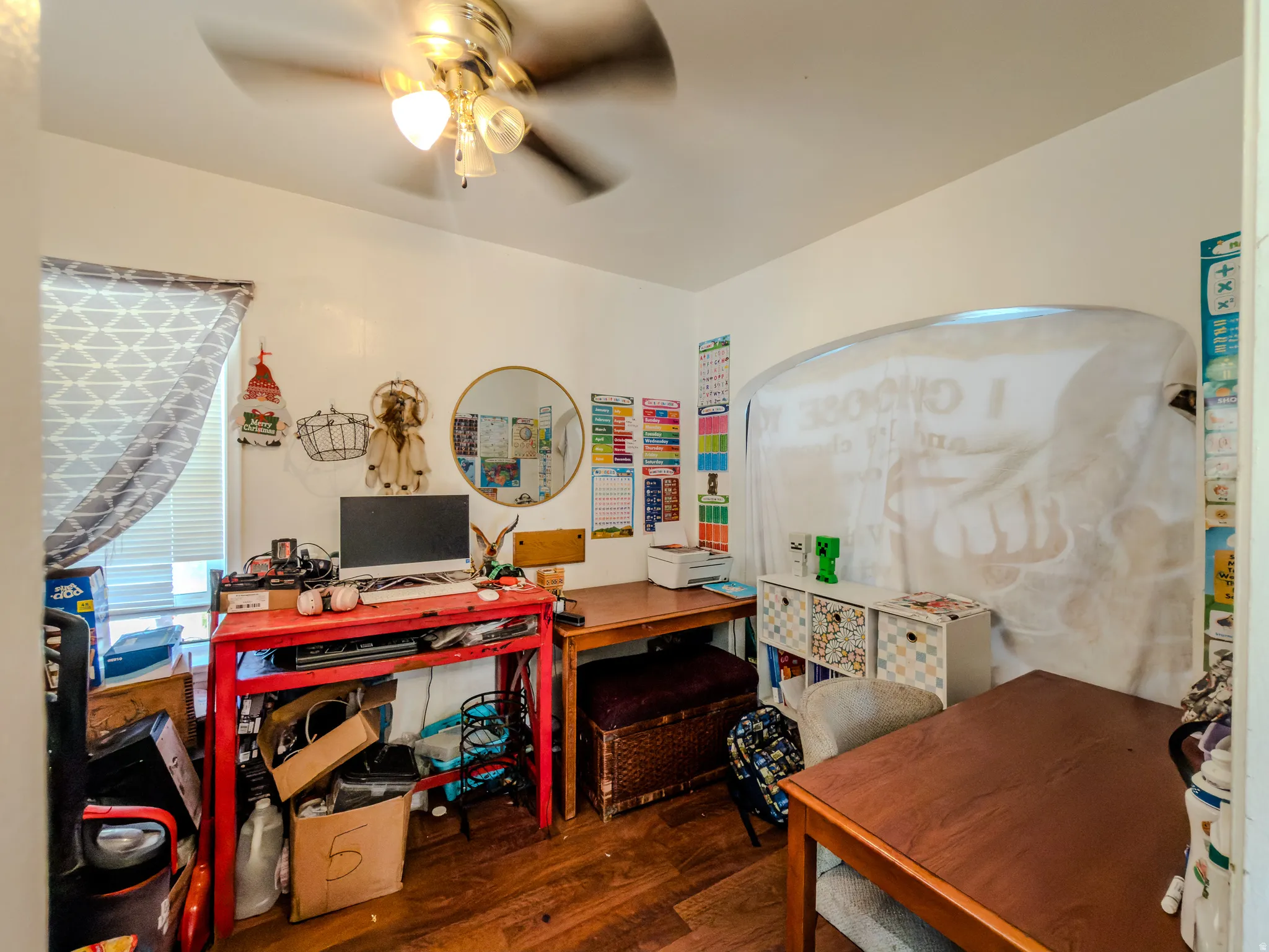 Home office with dark wood-style flooring and ceiling fan