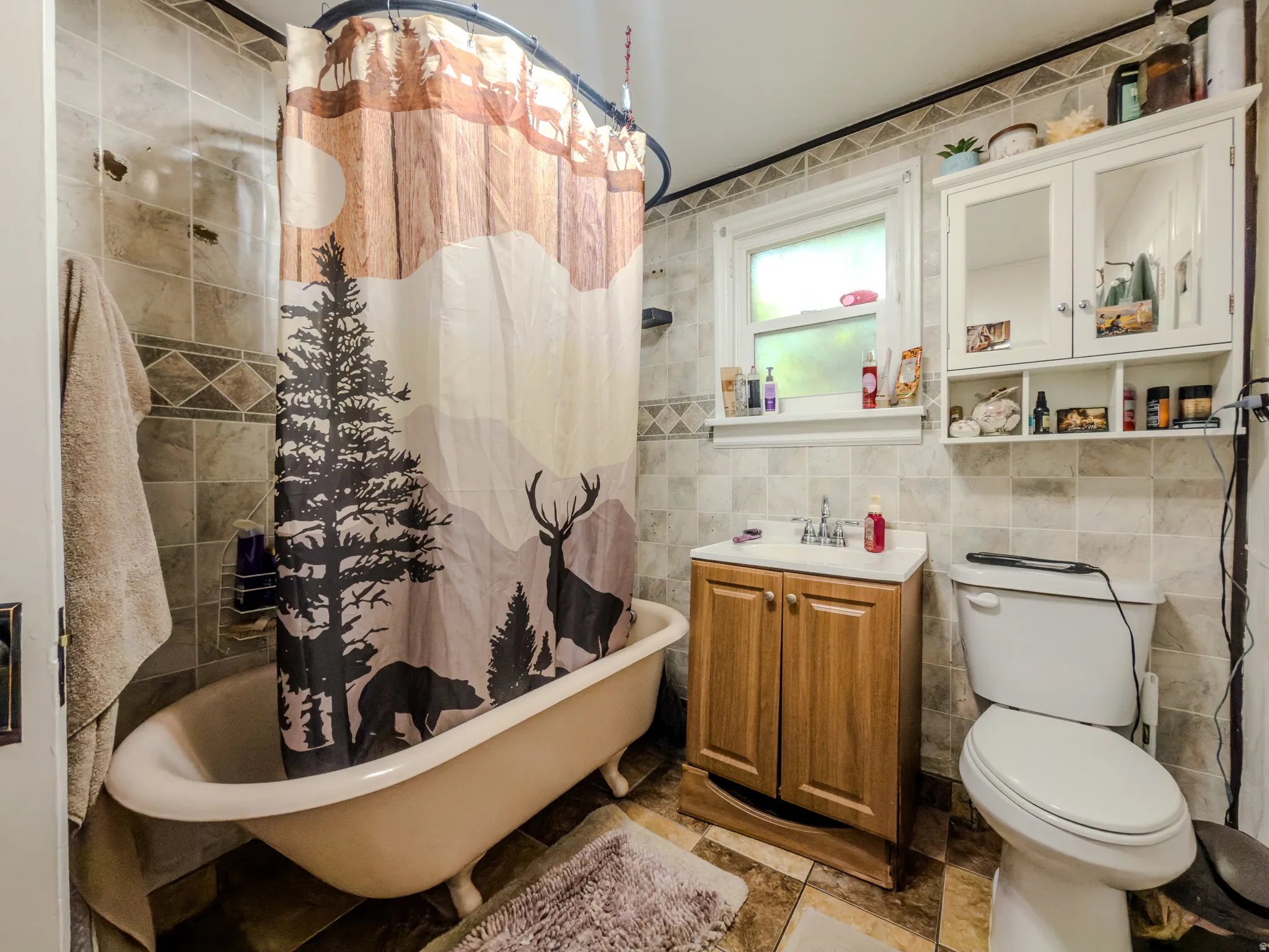 Bathroom featuring tile walls, vanity, and a combined bath / shower with freestanding tub