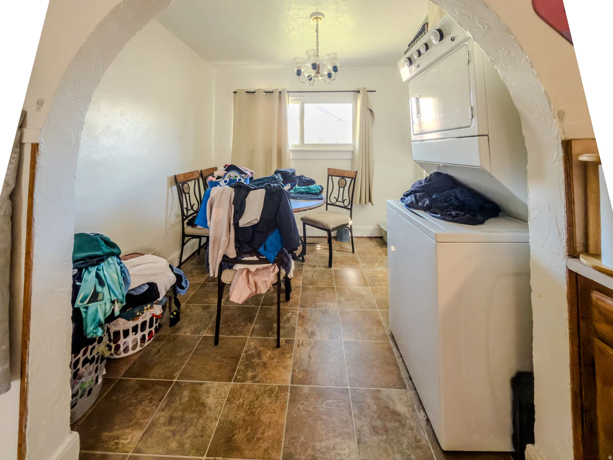 Laundry area with stacked washer / dryer, a chandelier, and arched walkways