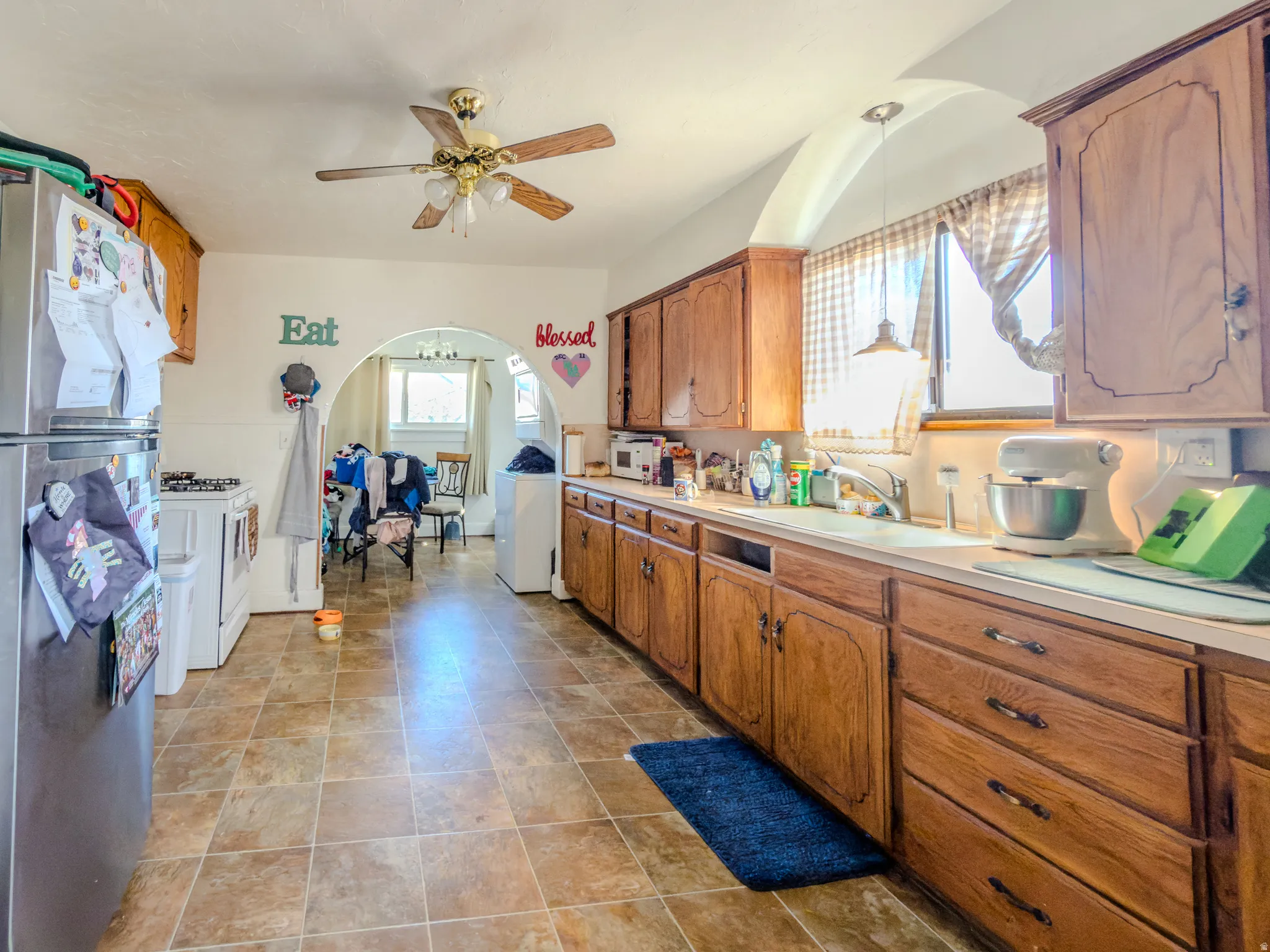 Kitchen with white appliances, light countertops, and wood finish cabinets