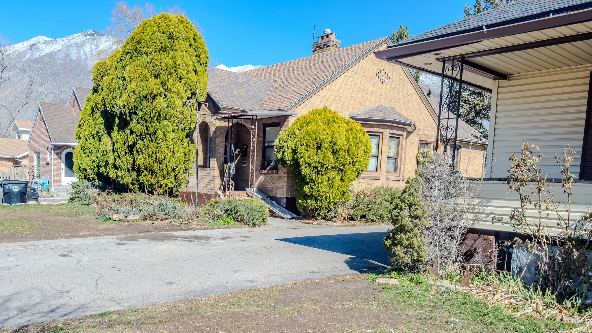 View of front of home with brick siding, a chimney, and a shingled roof