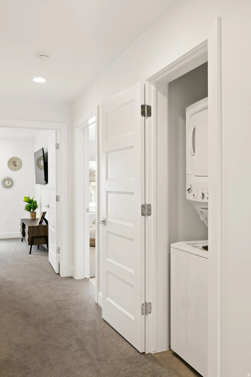 Laundry area featuring stacked washer / dryer, light carpet, and recessed lighting