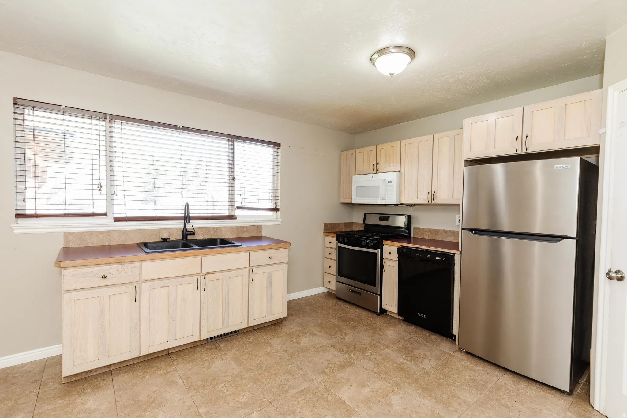Kitchen with stainless steel appliances and light wood finish cabinetry