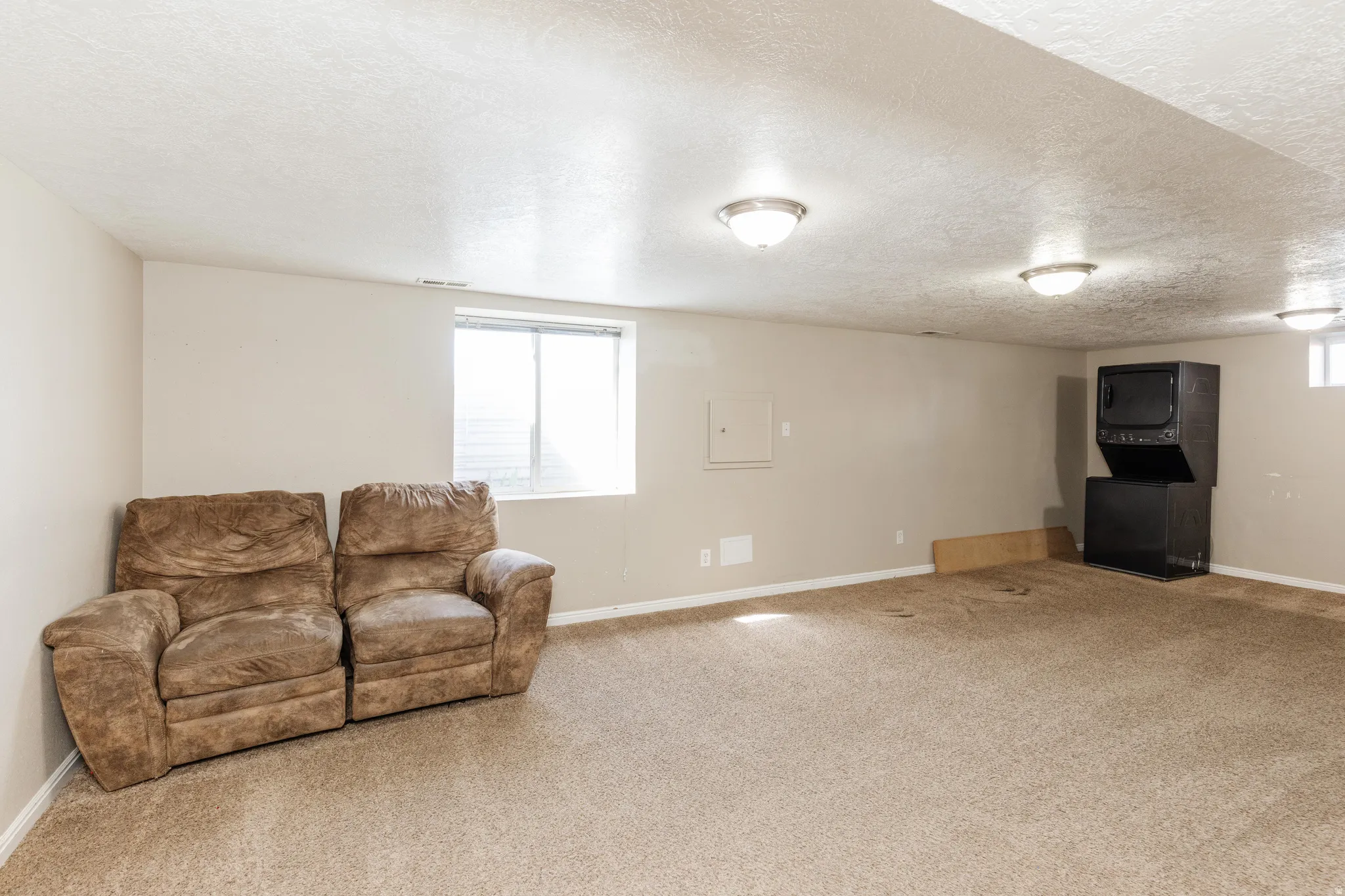Living room featuring a textured ceiling, light carpet, and electric panel