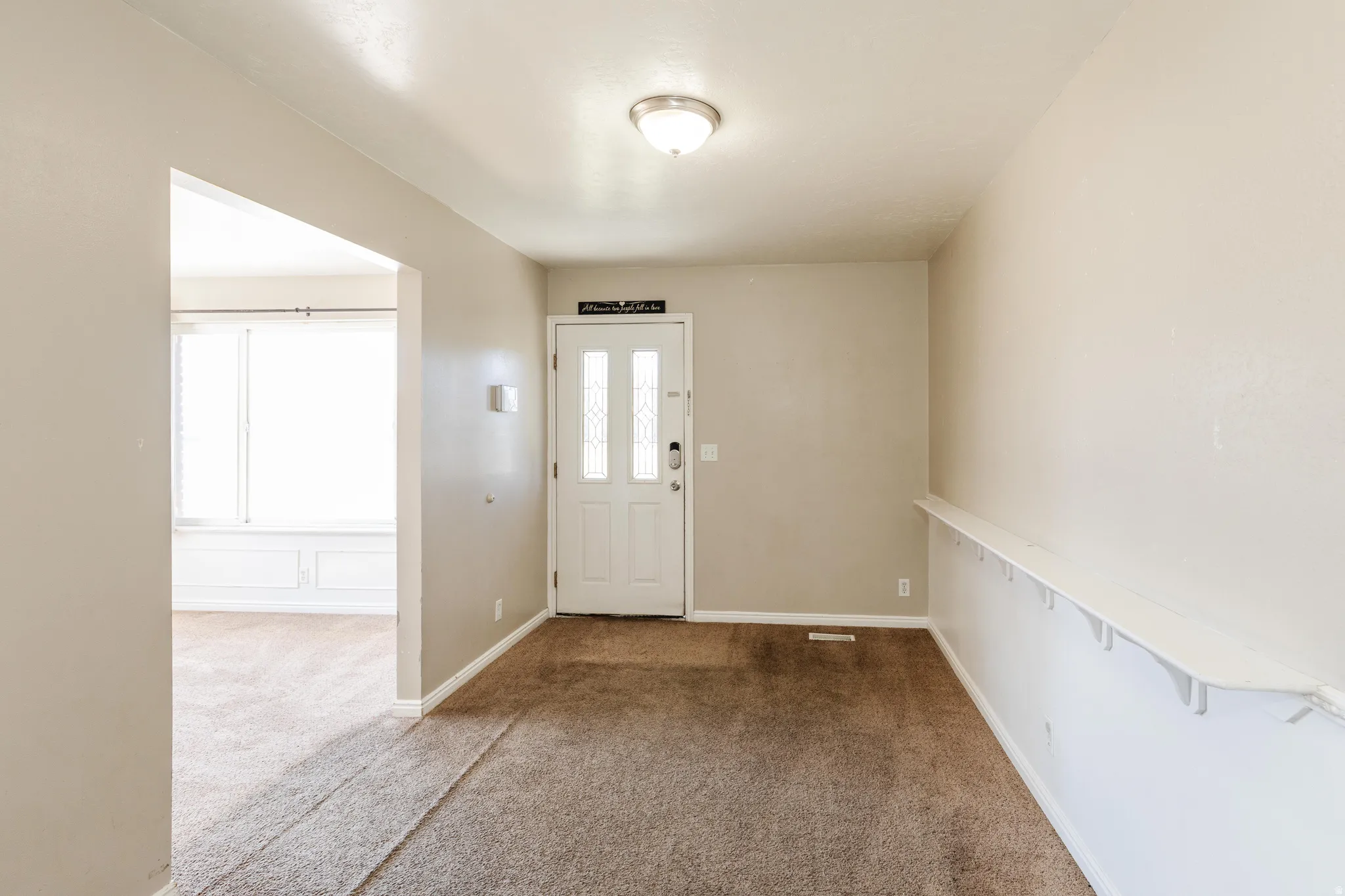 Carpeted foyer featuring baseboards