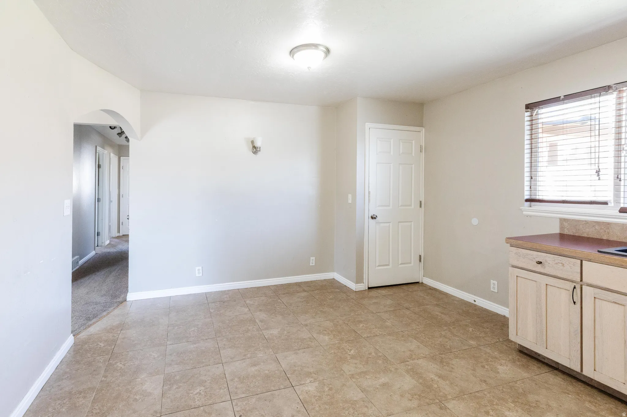 Unfurnished dining area featuring arched walkways and light tile patterned flooring