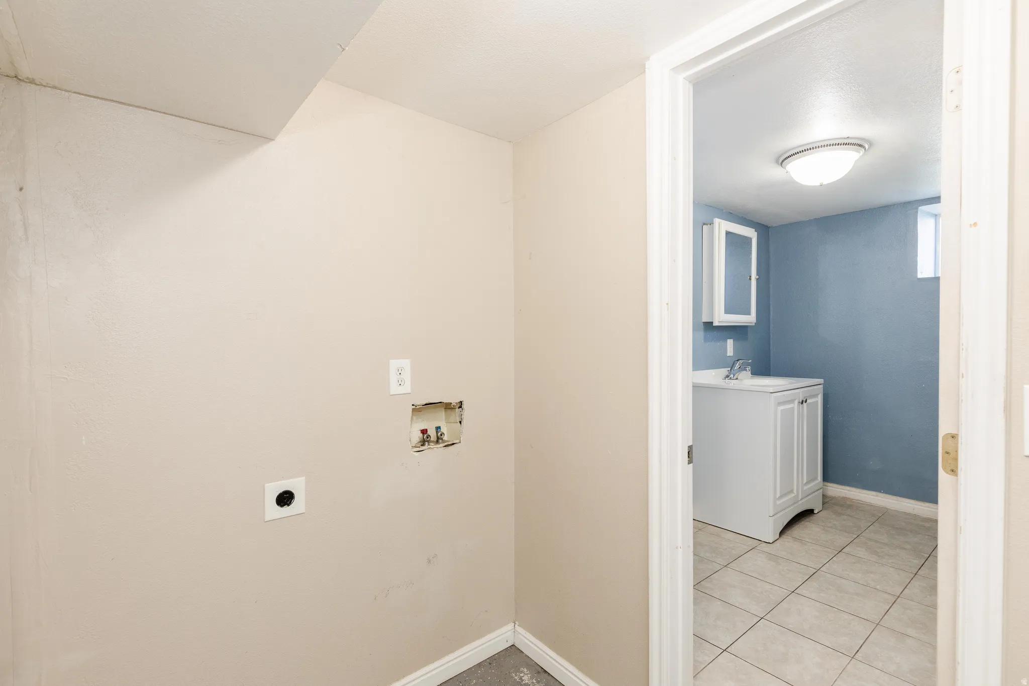 Laundry area with light tile patterned floors, hookup for a washing machine, and hookup for an electric dryer