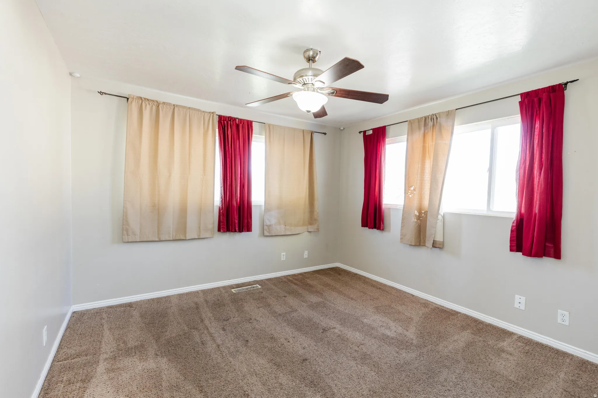 Carpeted empty room with baseboards and a ceiling fan