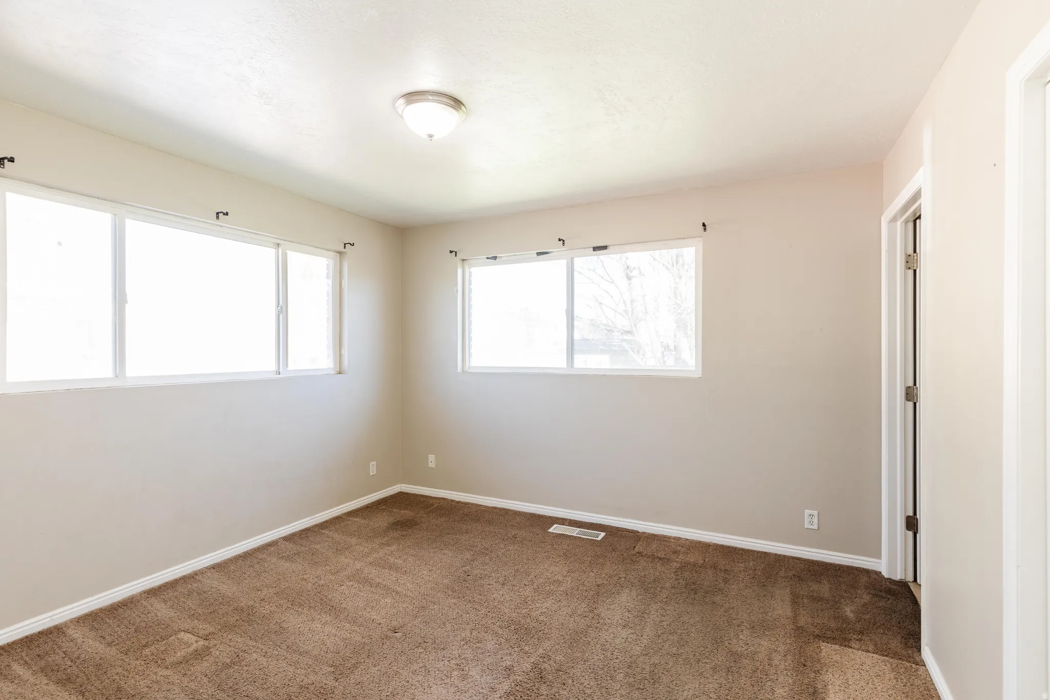 Spare room featuring dark colored carpet and baseboards