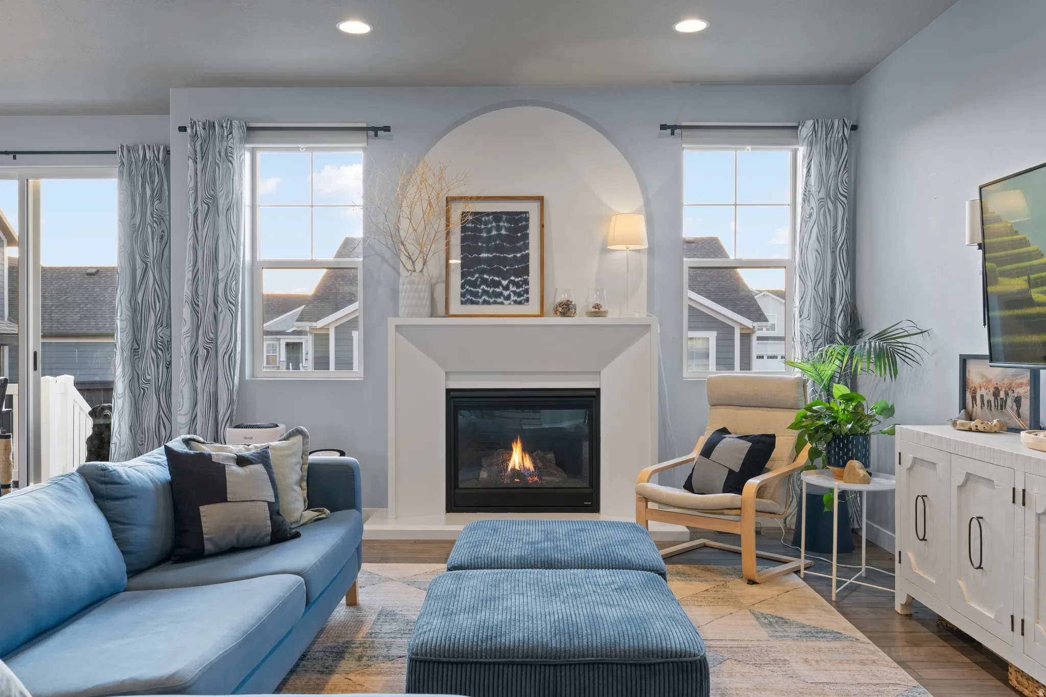 Living area featuring a glass covered fireplace, wood finished floors, recessed lighting, and plenty of natural light
