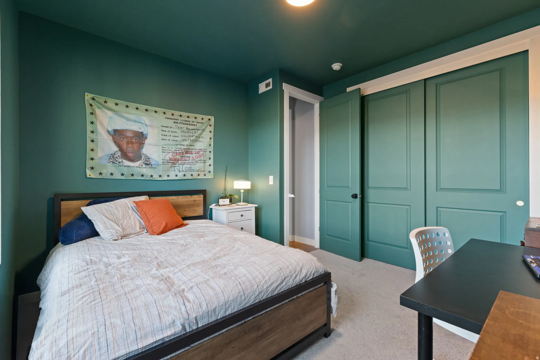 Bedroom featuring light carpet, a closet, and a desk