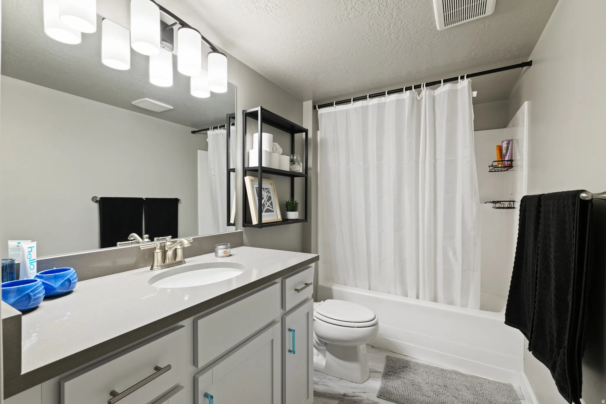 Full bathroom with a textured ceiling, vanity, and shower / tub combo