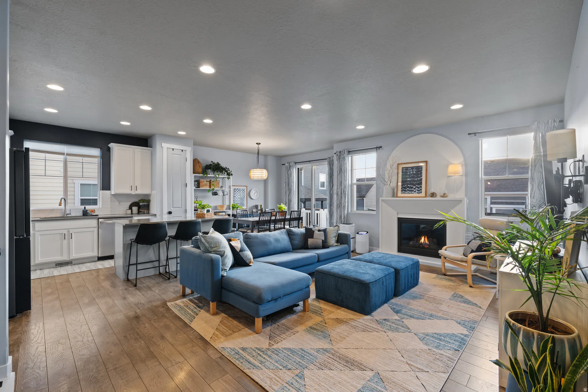 Living room with a glass covered fireplace, light wood finished floors, healthy amount of natural light, and recessed lighting