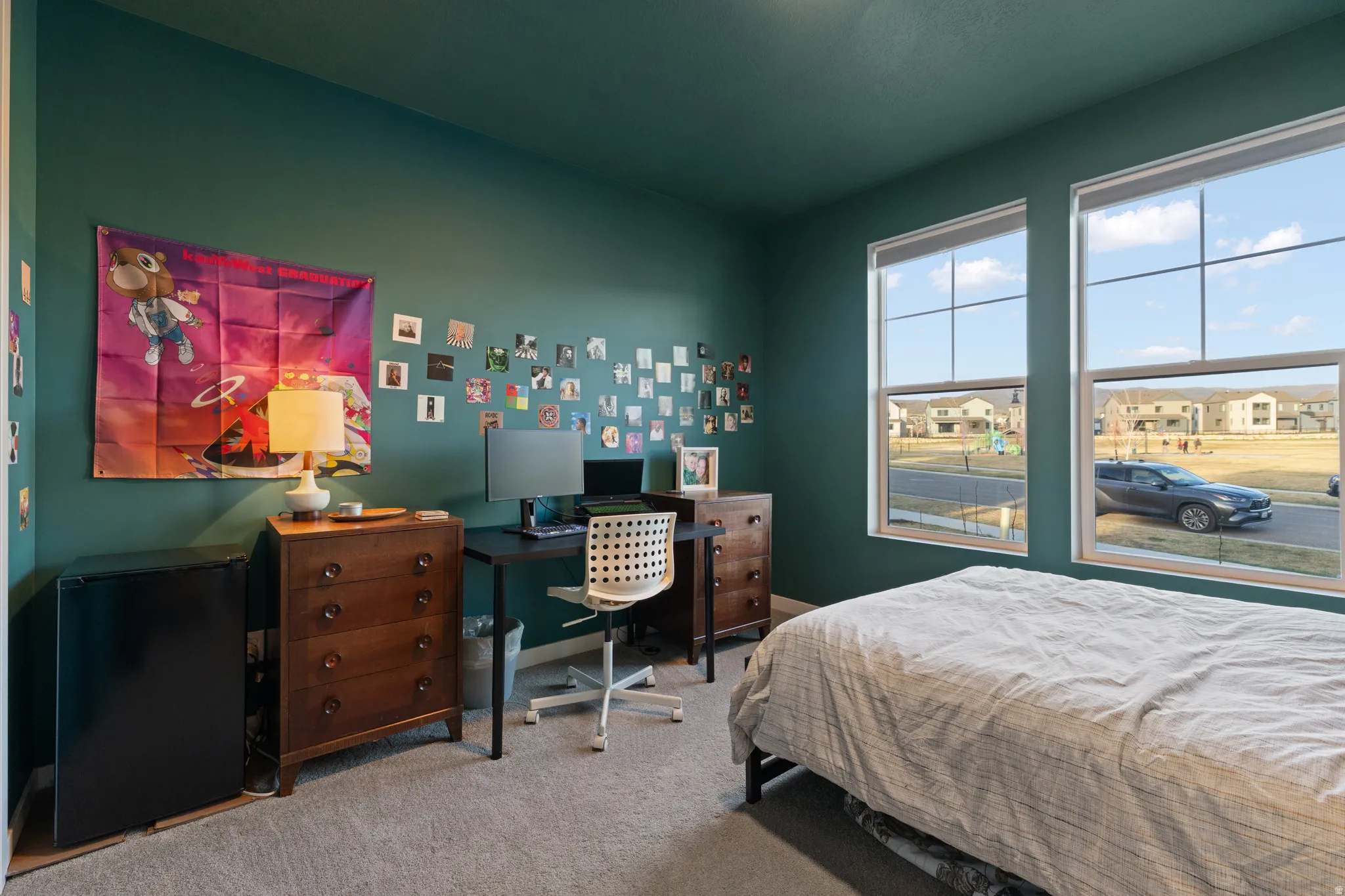 Bedroom with light carpet, black refrigerator, and an office area