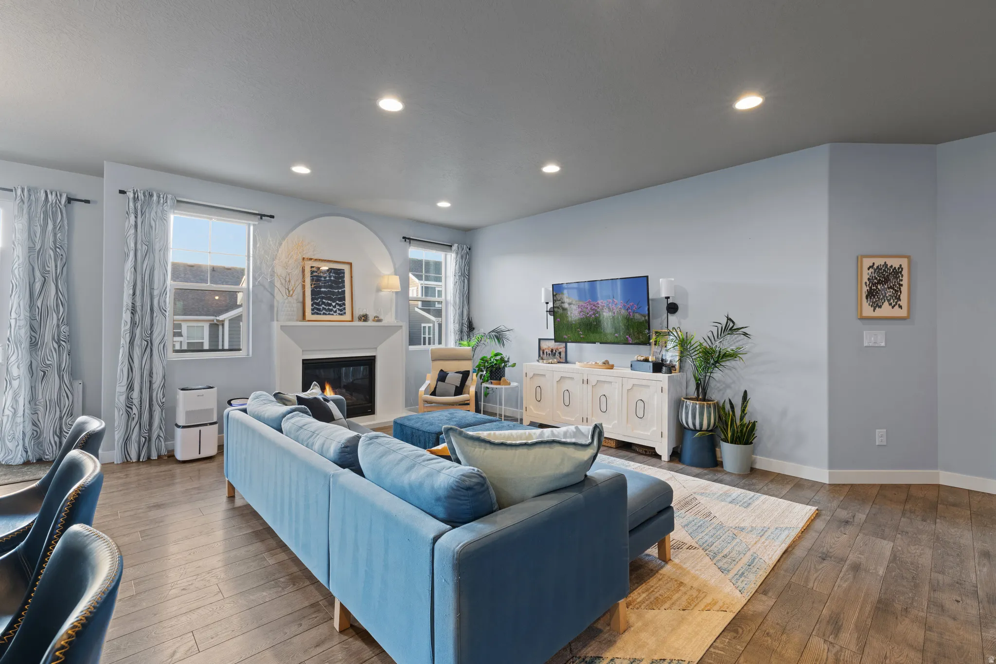 Living room featuring hardwood / wood-style floors, a glass covered fireplace, and recessed lighting