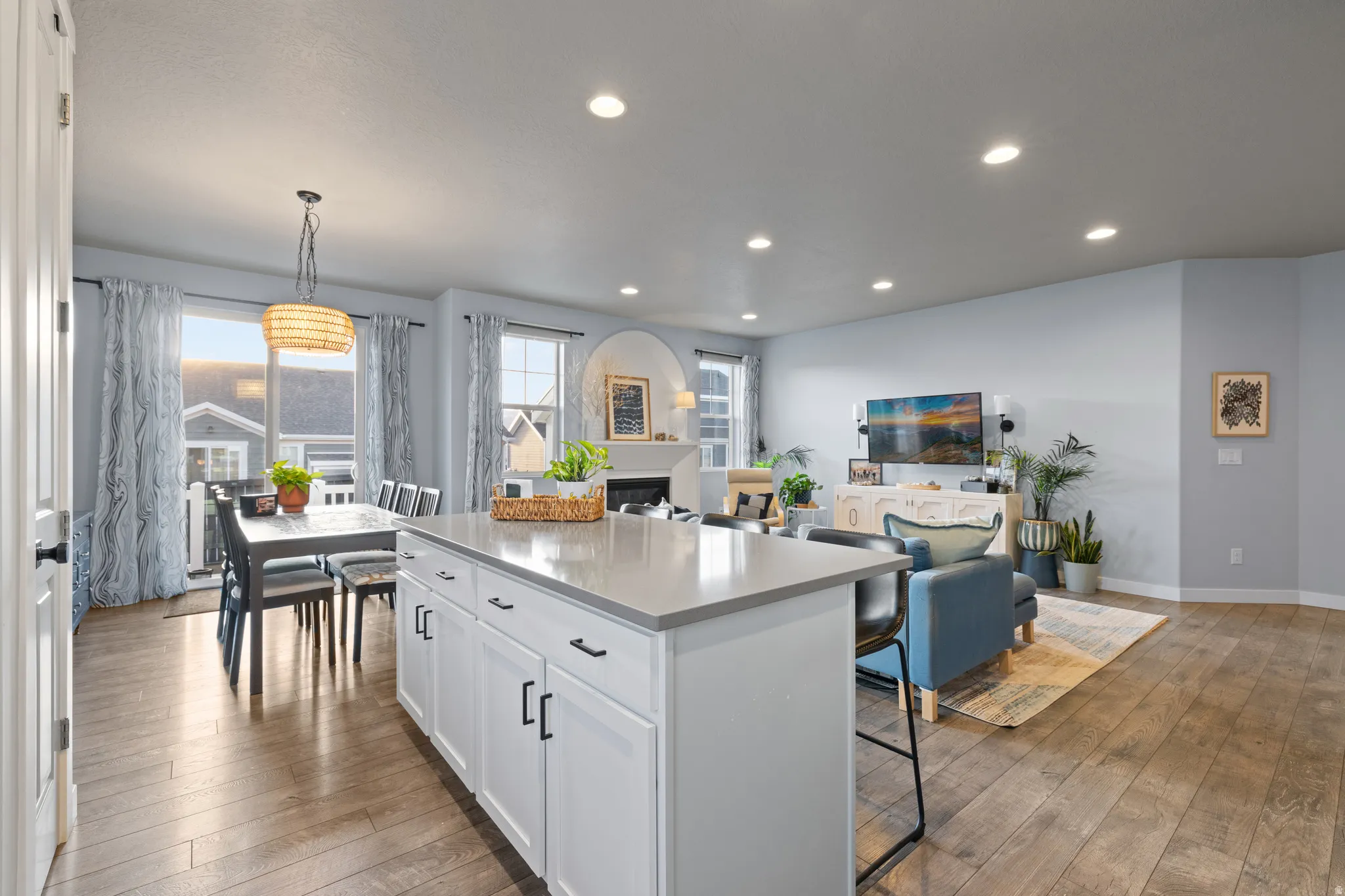 Kitchen with open floor plan, a center island, white cabinetry, light wood-style floors, and a kitchen bar