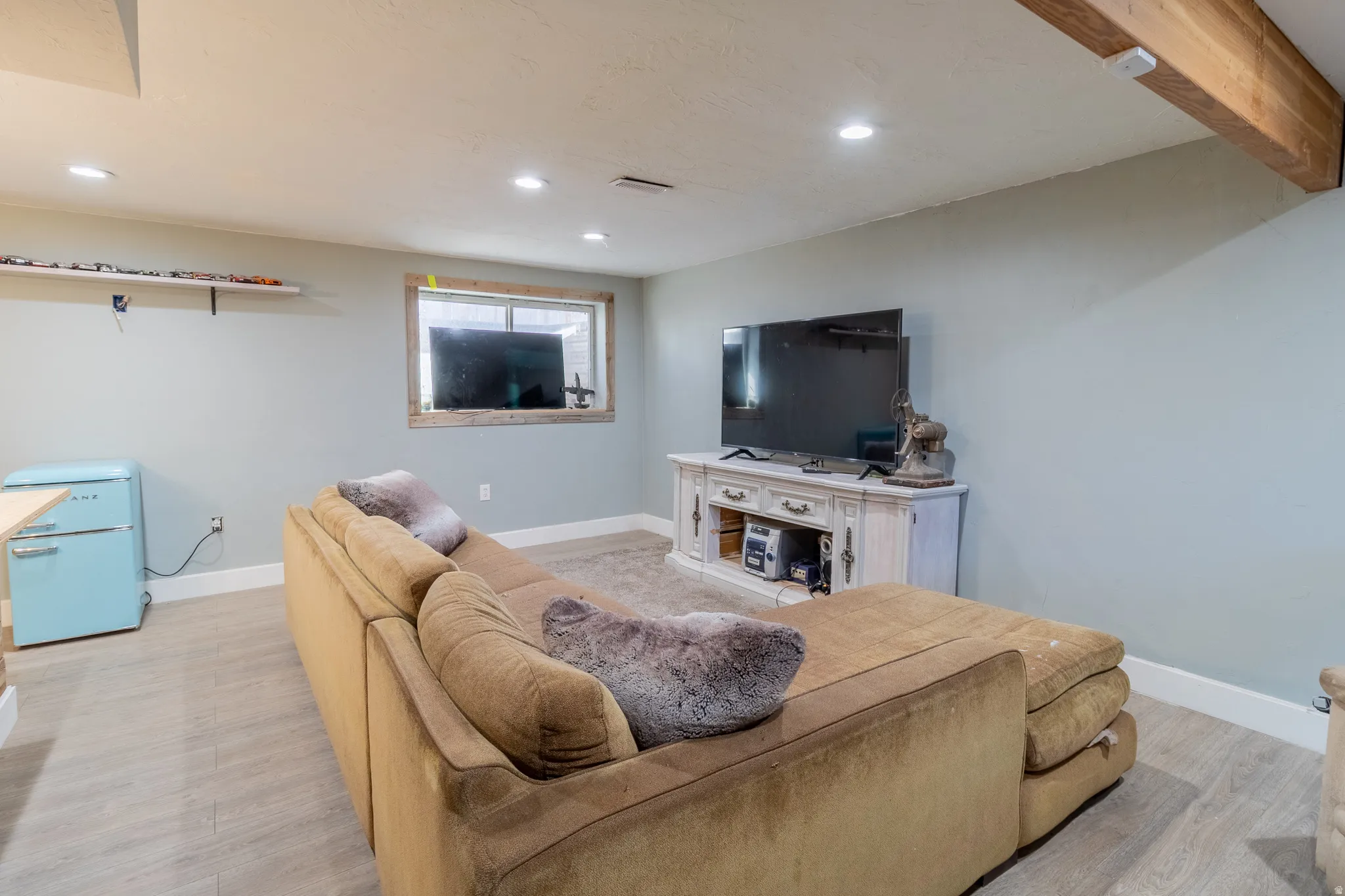 Living area with light wood finished floors, recessed lighting, and beam ceiling