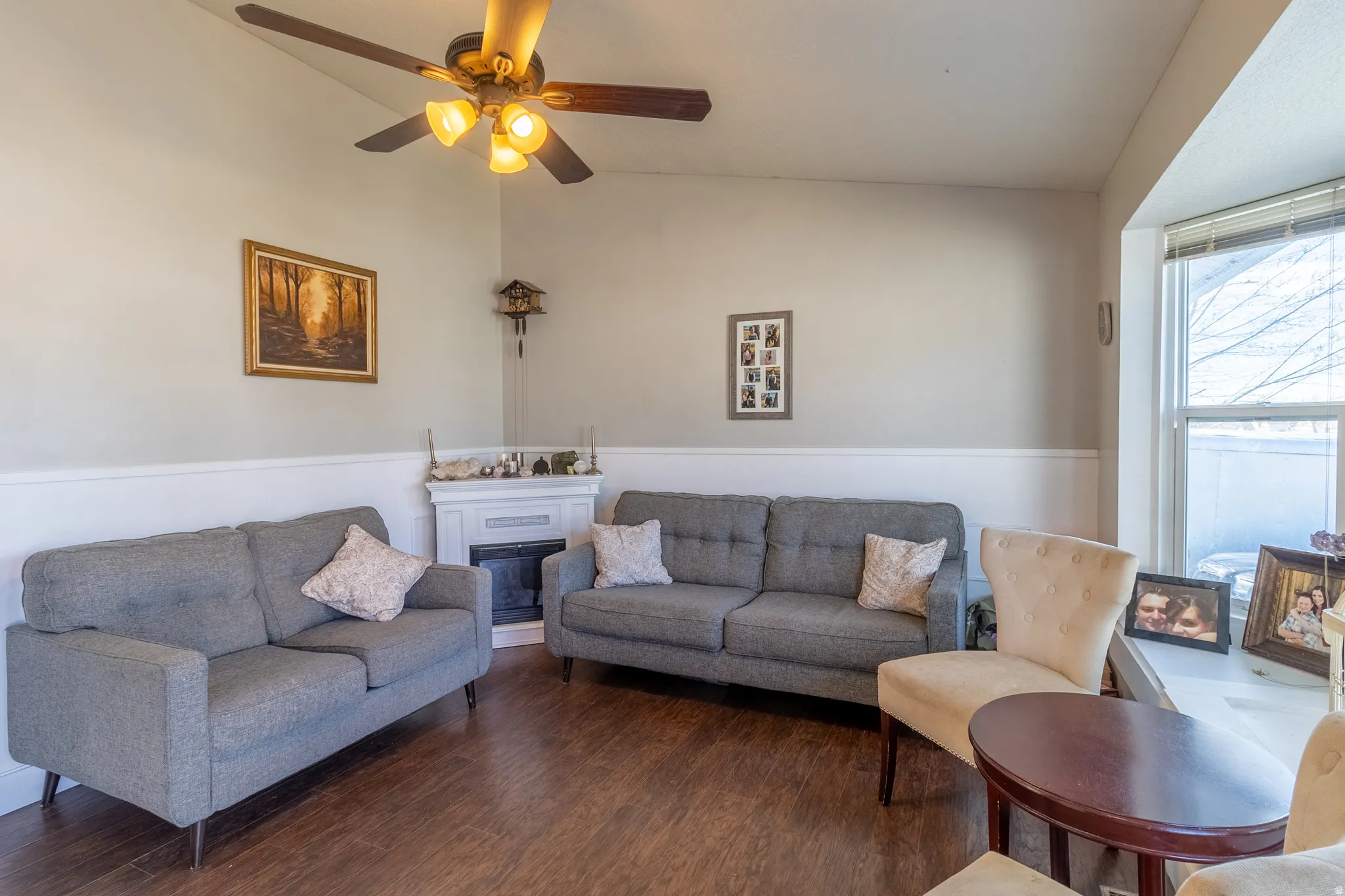 Living area with vaulted ceiling, wood finished floors, ceiling fan, and a glass covered fireplace
