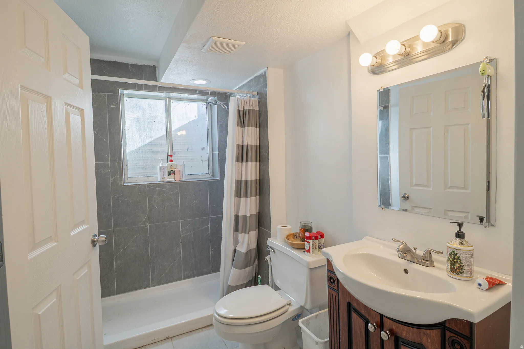 Full bath with vanity, a stall shower, and a textured ceiling