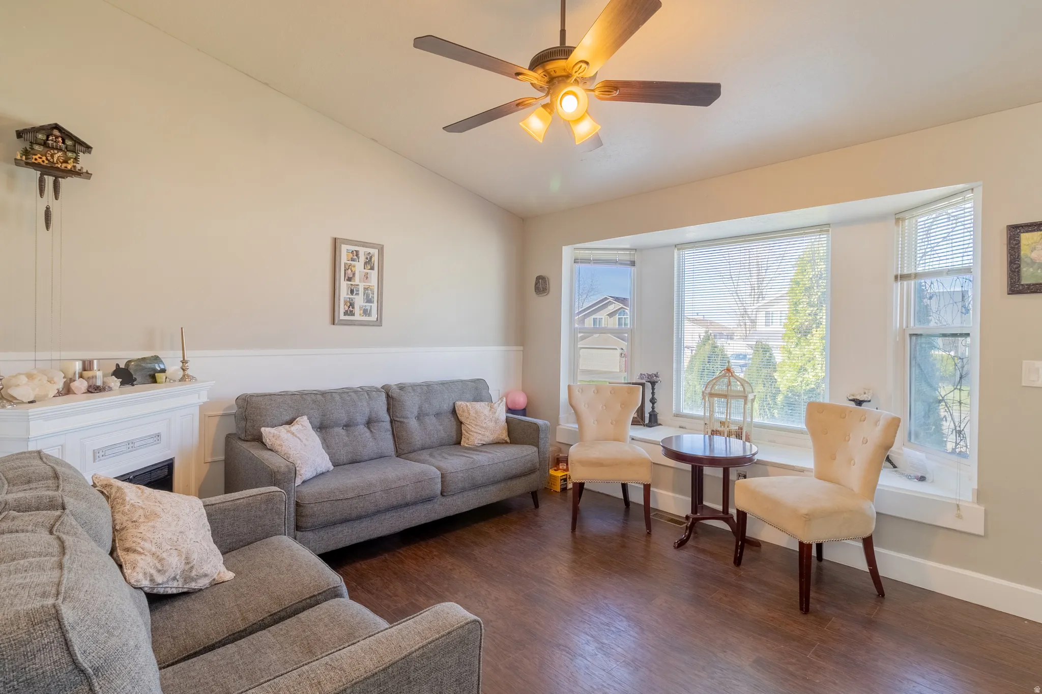 Living room featuring dark wood finished floors, lofted ceiling, a ceiling fan, and a fireplace