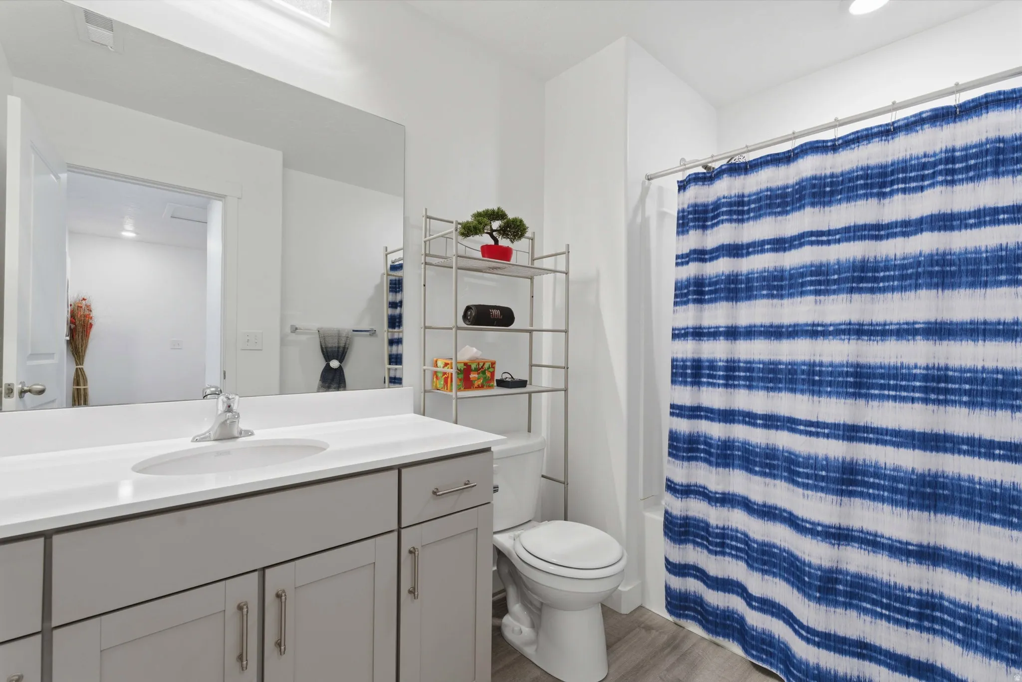Full bath featuring vanity, light wood finished floors, shower / tub combo, and recessed lighting
