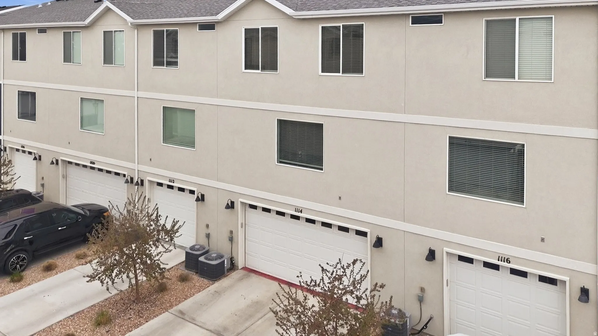View of garage, concrete driveway, and stucco siding