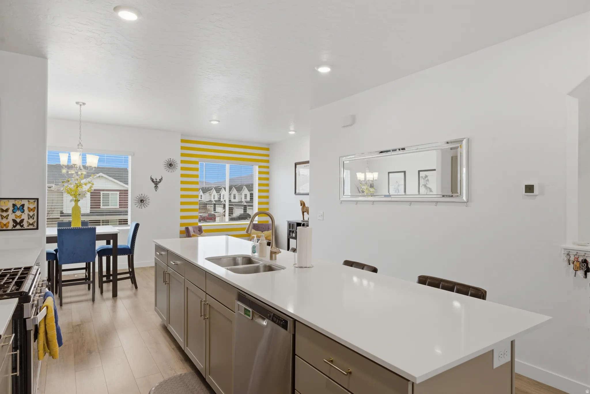 Kitchen featuring an island with sink, stainless steel appliances, light wood-style floors, a kitchen breakfast bar, and suspended lighting