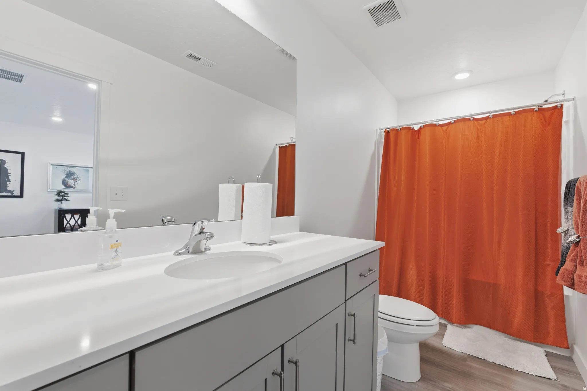 Bathroom with vanity, light wood-style flooring, shower / bath combination with curtain, and recessed lighting