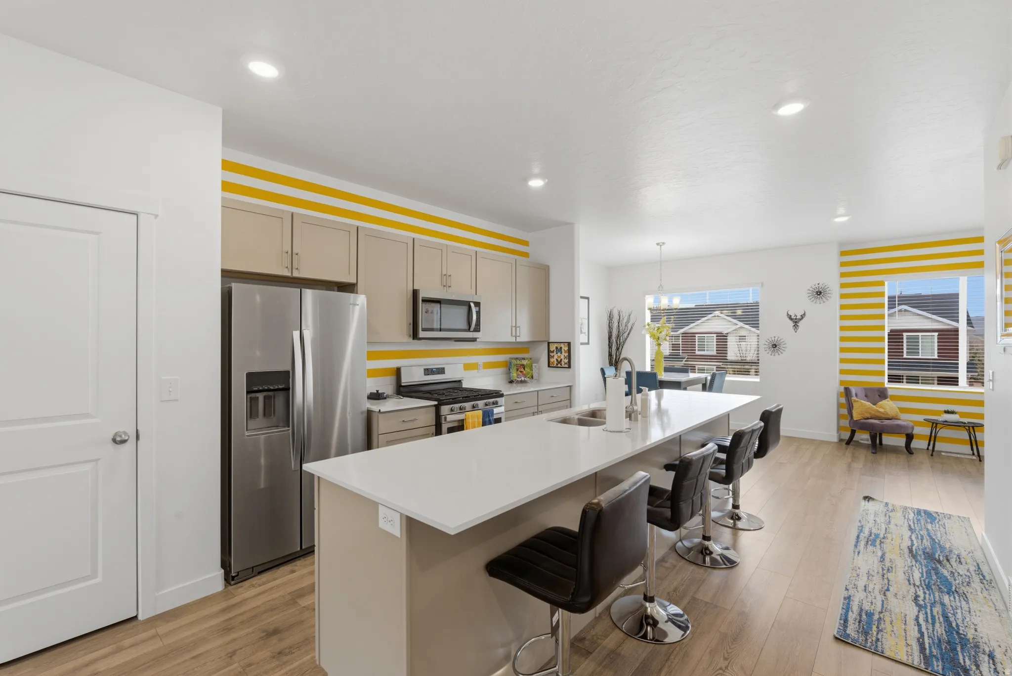 Kitchen featuring stainless steel appliances, an island with sink, a breakfast bar area, and light wood finished floors