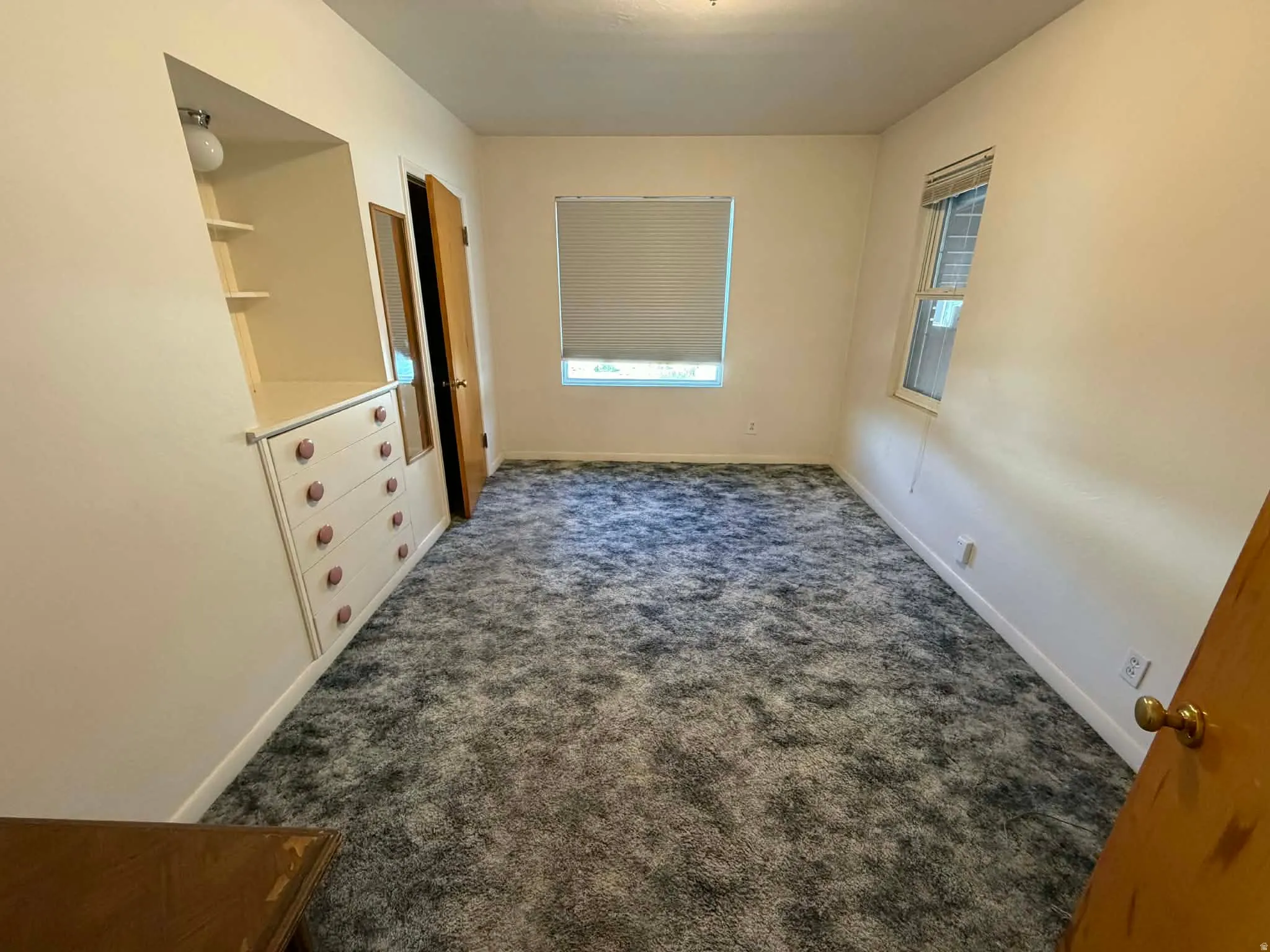 Unfurnished bedroom with dark colored carpet and baseboards
