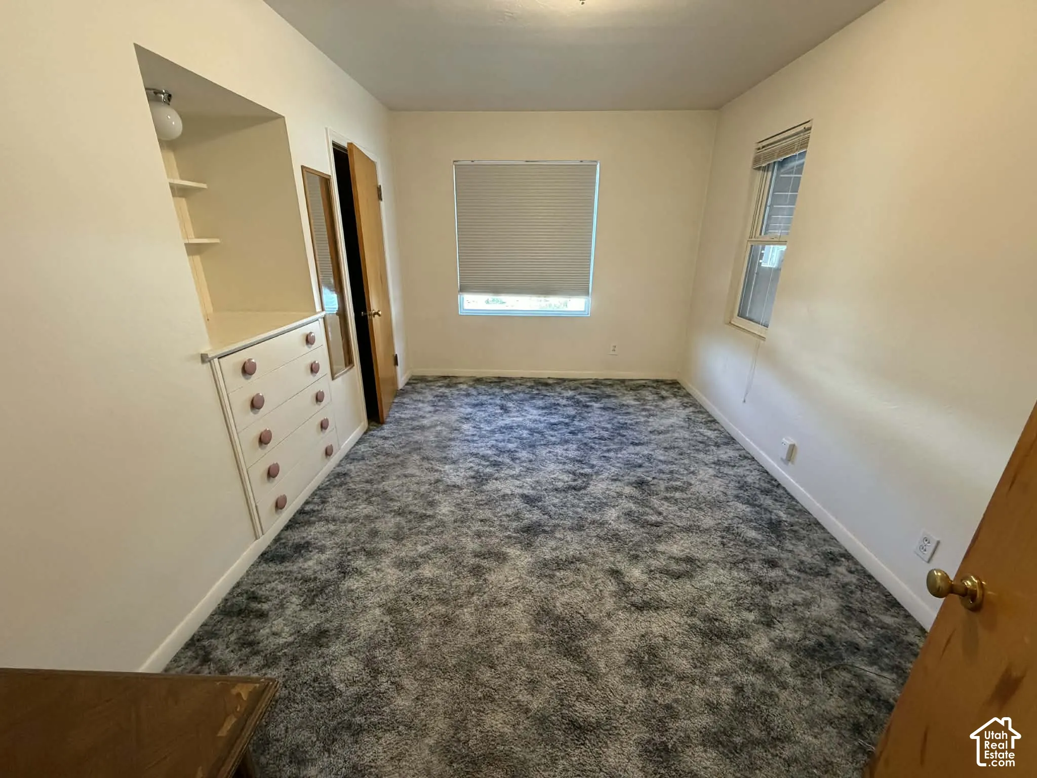 Unfurnished bedroom with dark colored carpet and baseboards