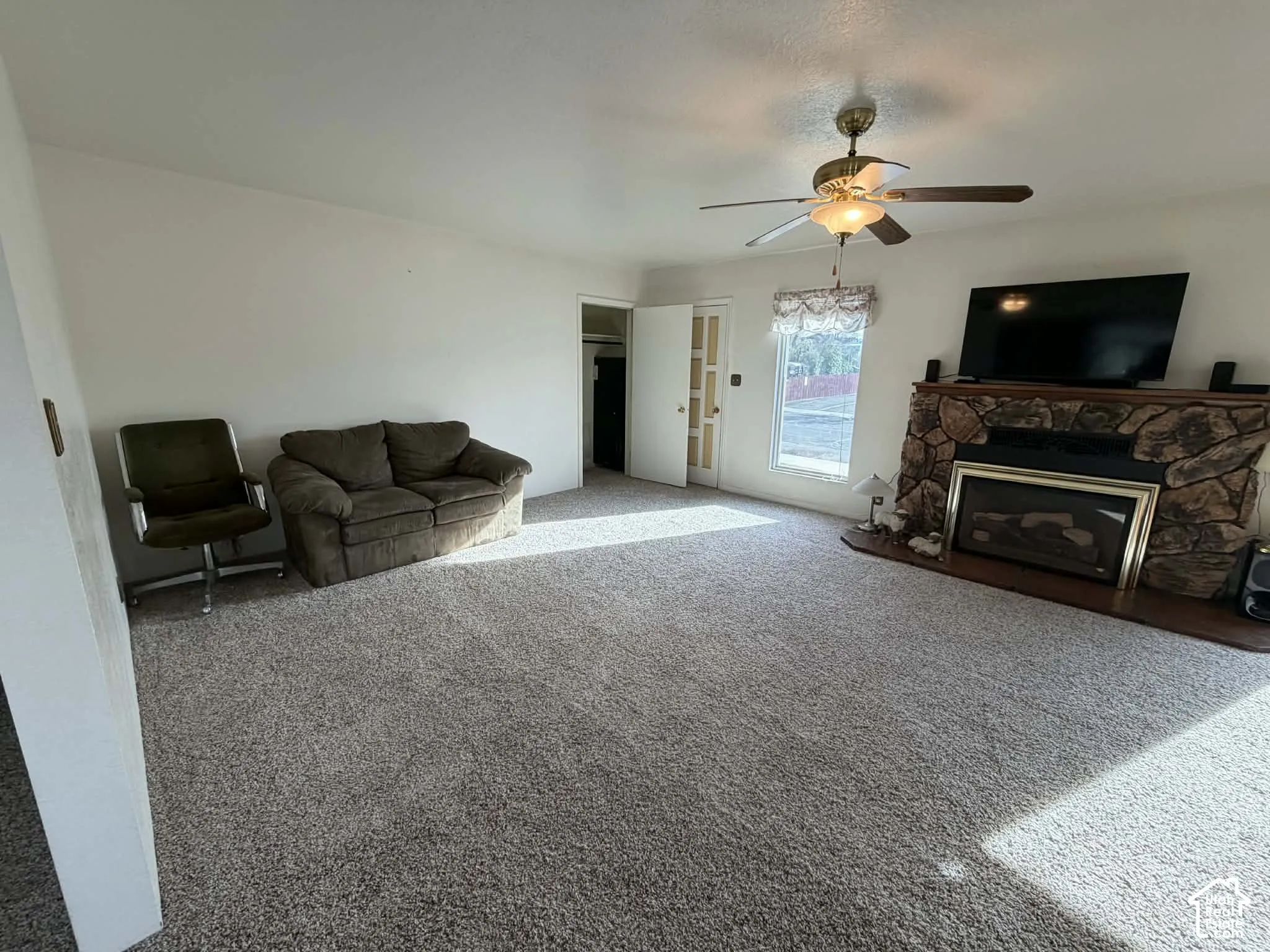 Carpeted living room with a fireplace and a ceiling fan