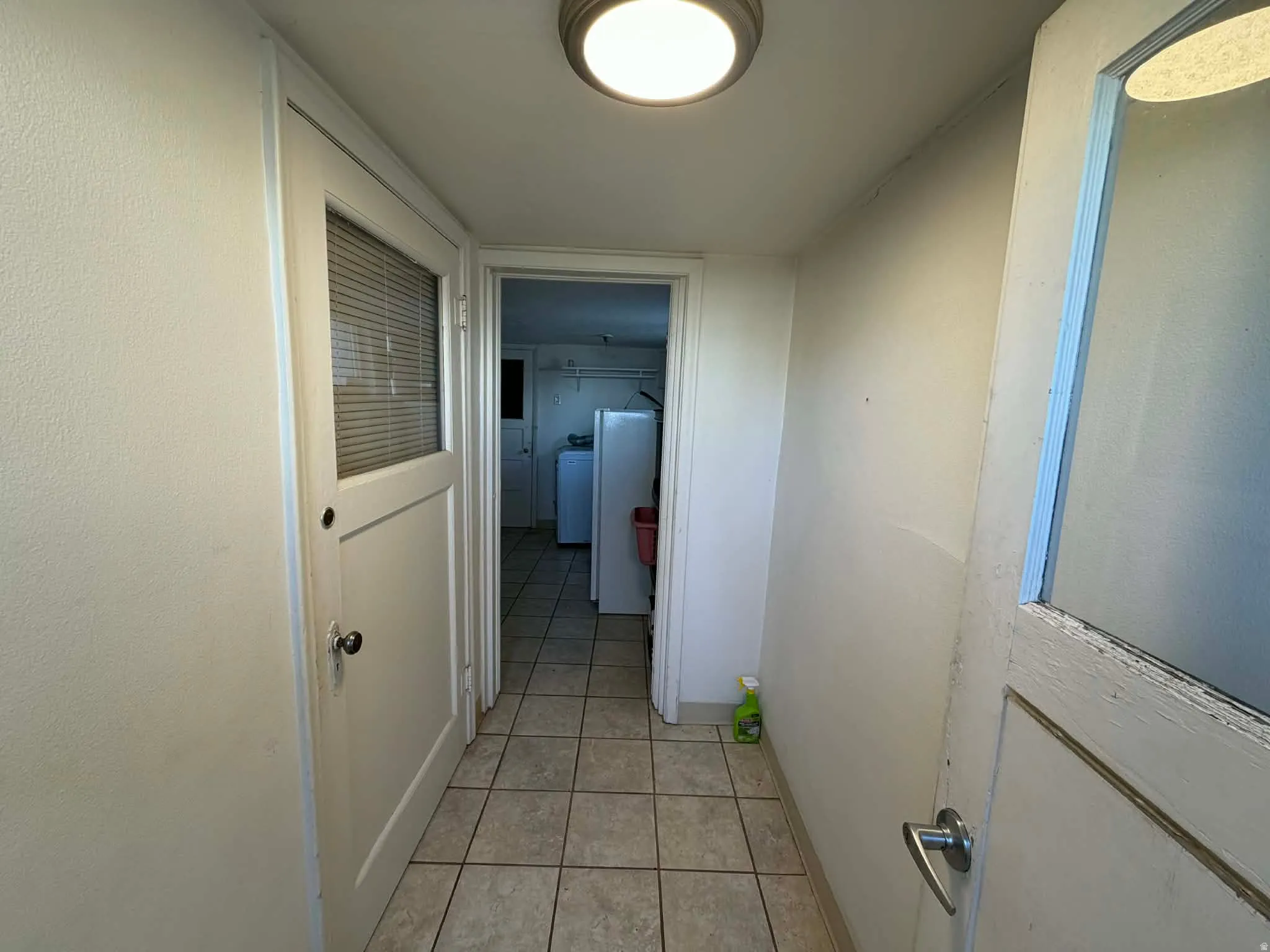 Hall with light tile patterned floors and independent washer and dryer