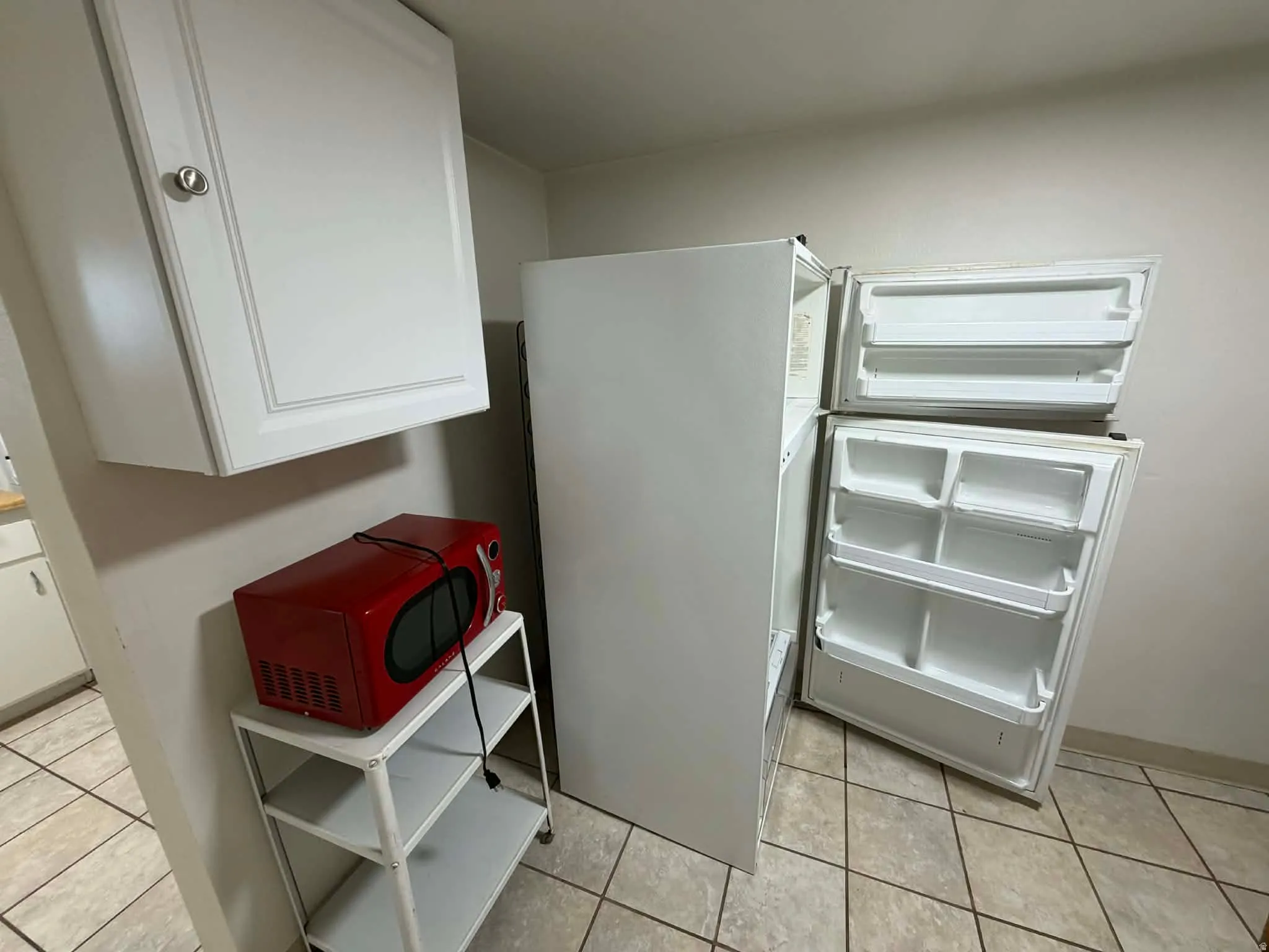 Kitchen with white cabinets, freestanding refrigerator, and light tile patterned floors