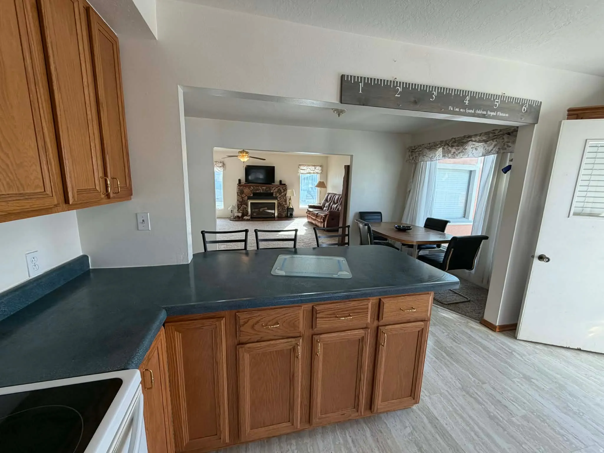 Kitchen featuring wood finish cabinets, dark countertops, range with electric cooktop, a peninsula, and light wood finished floors
