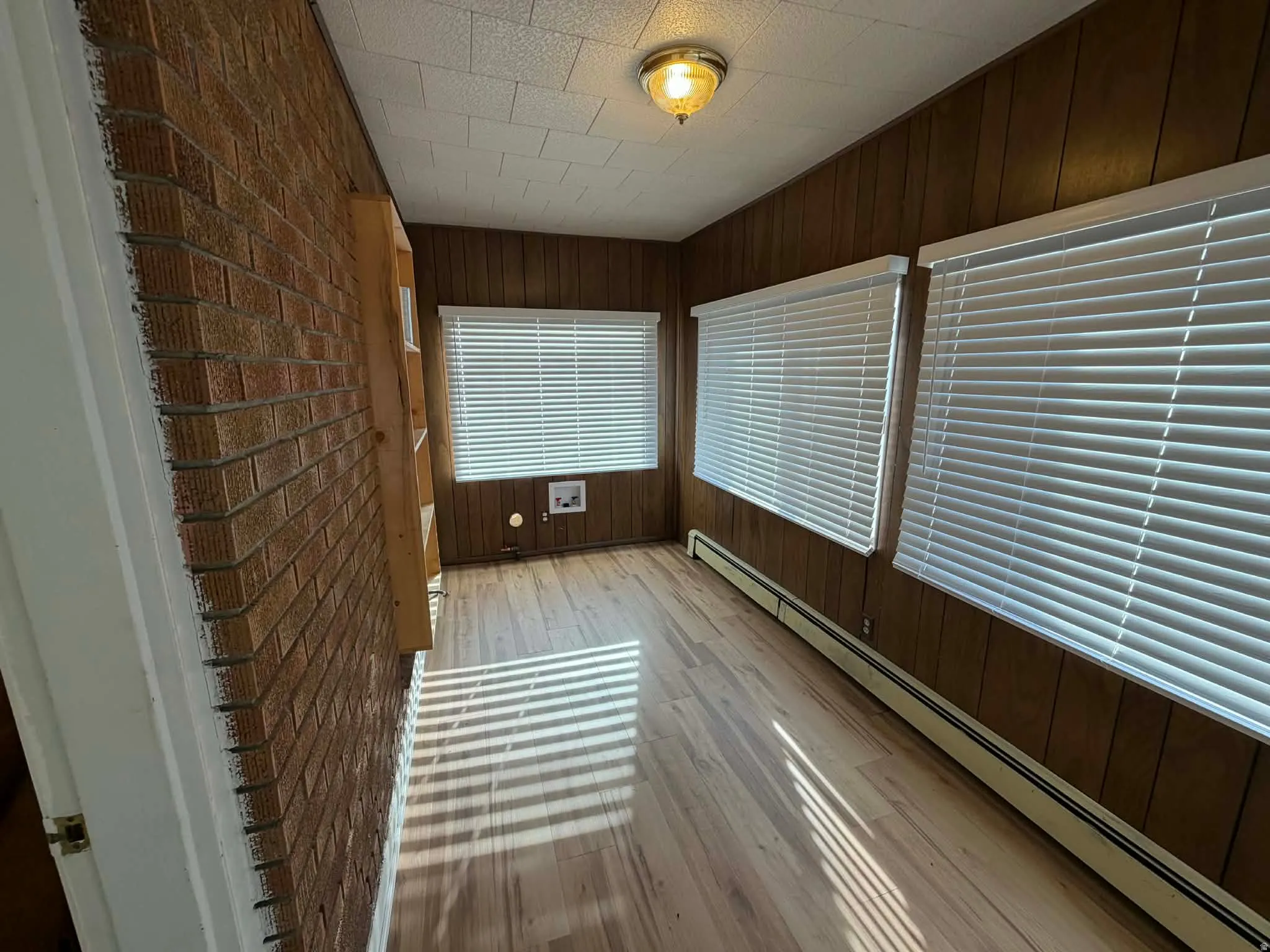 Unfurnished sunroom featuring a baseboard heating unit