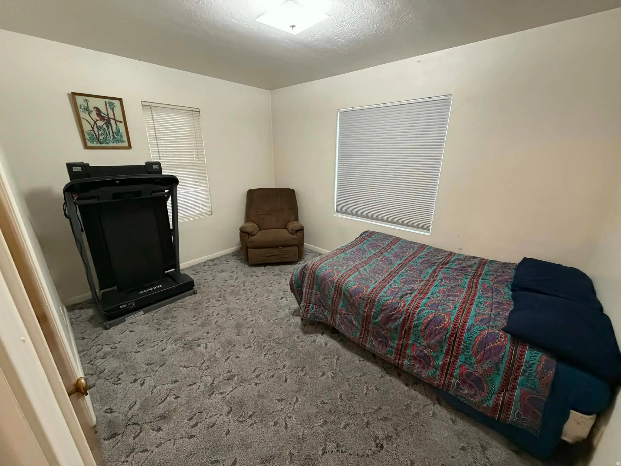 Carpeted bedroom featuring baseboards and a textured ceiling