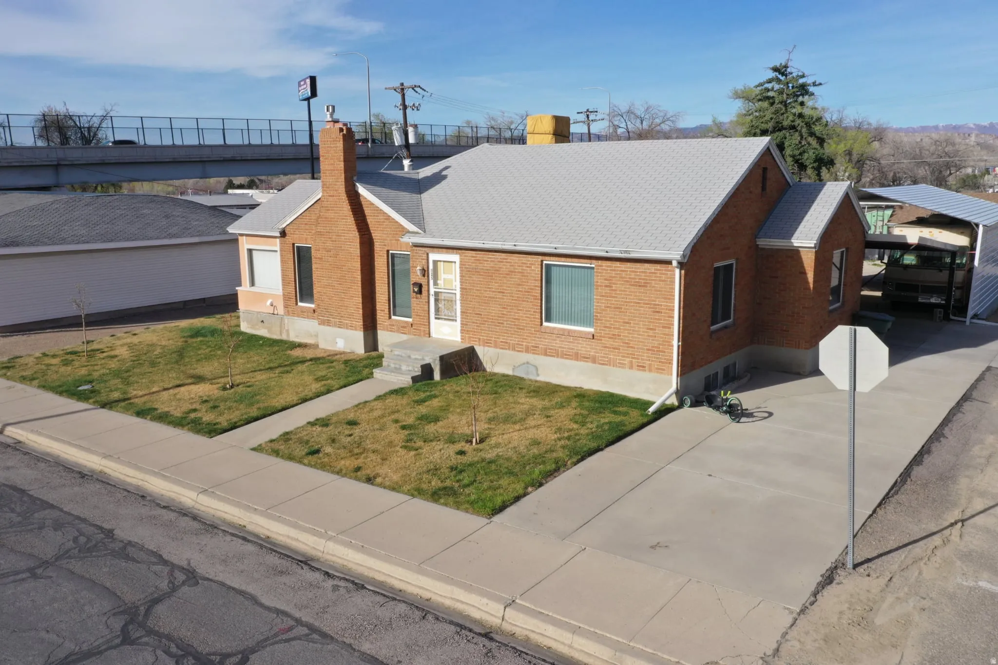 Ranch-style house featuring brick siding, a front lawn, a chimney, and roof with shingles